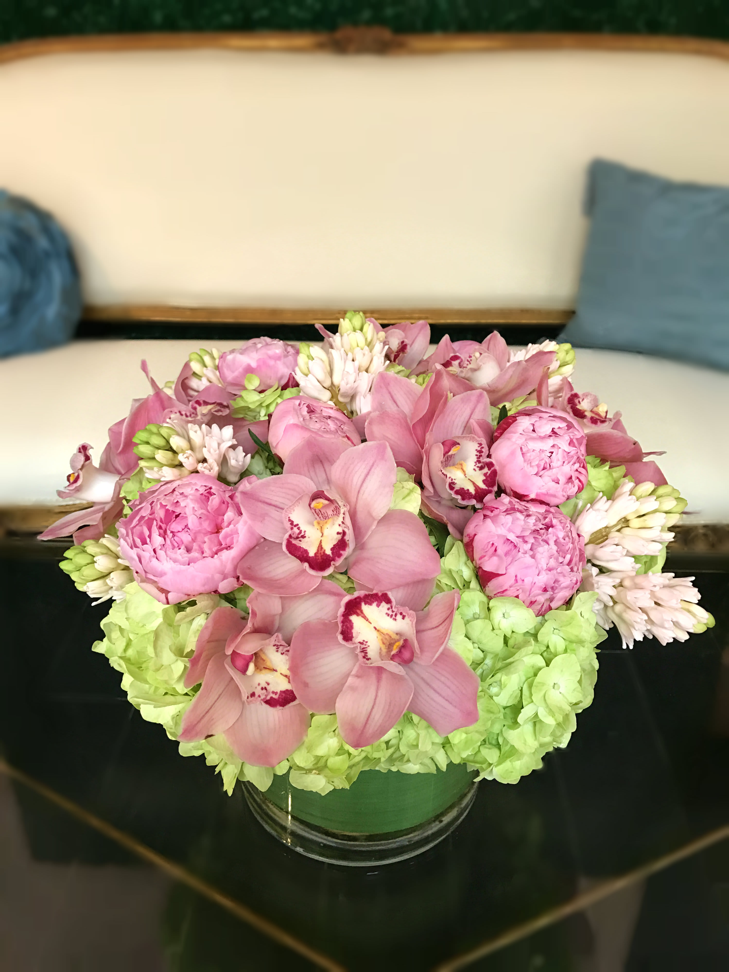 Green and Purple Affair - The perfect duo of orchids and peonies on a bed of hydgrangeas in a glass vase.