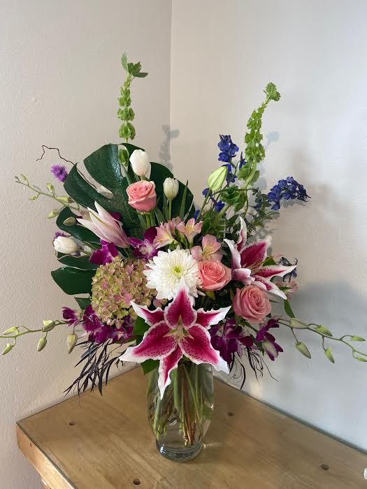 Thinkin' Bout You - Fun and fragrant!  Lilies, bells of Ireland, orchids, hydrangea, and more are gathered in a clear vase.  Call shop to discuss what we have in stock.