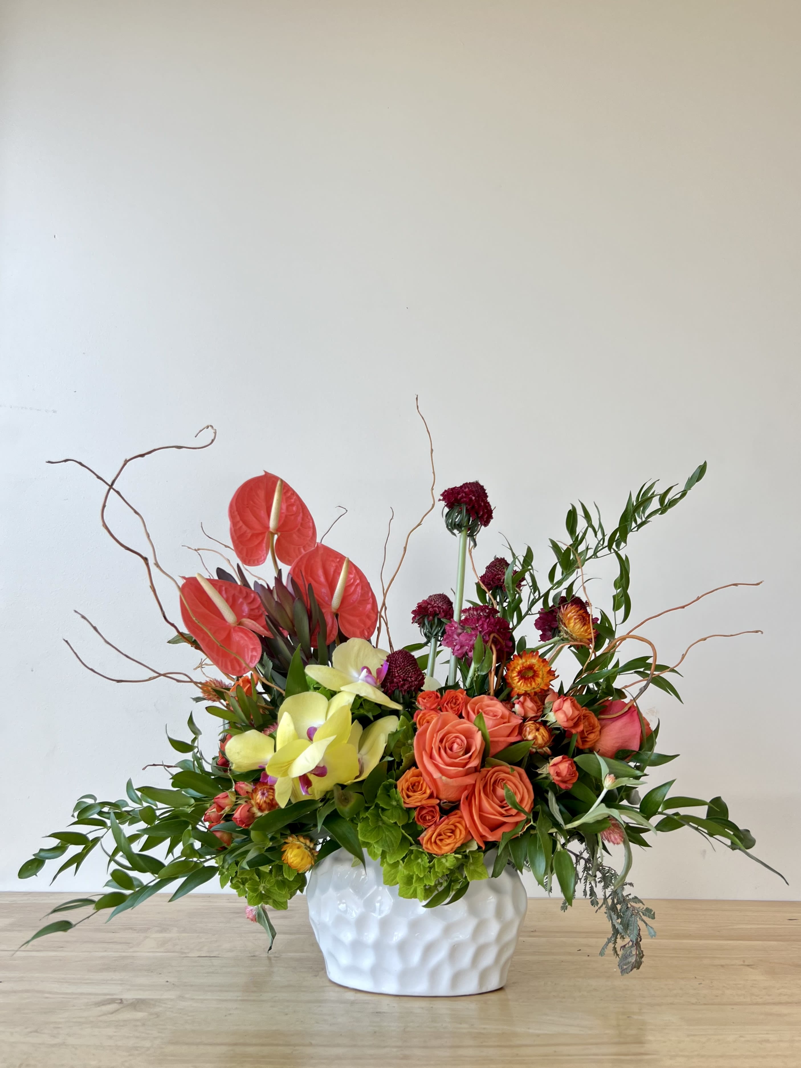 Sunrise - Beautiful one-sided arrangement with our seasonal mix florals, roses, hydrangeas, roses, orchids, anthuriums, and more.