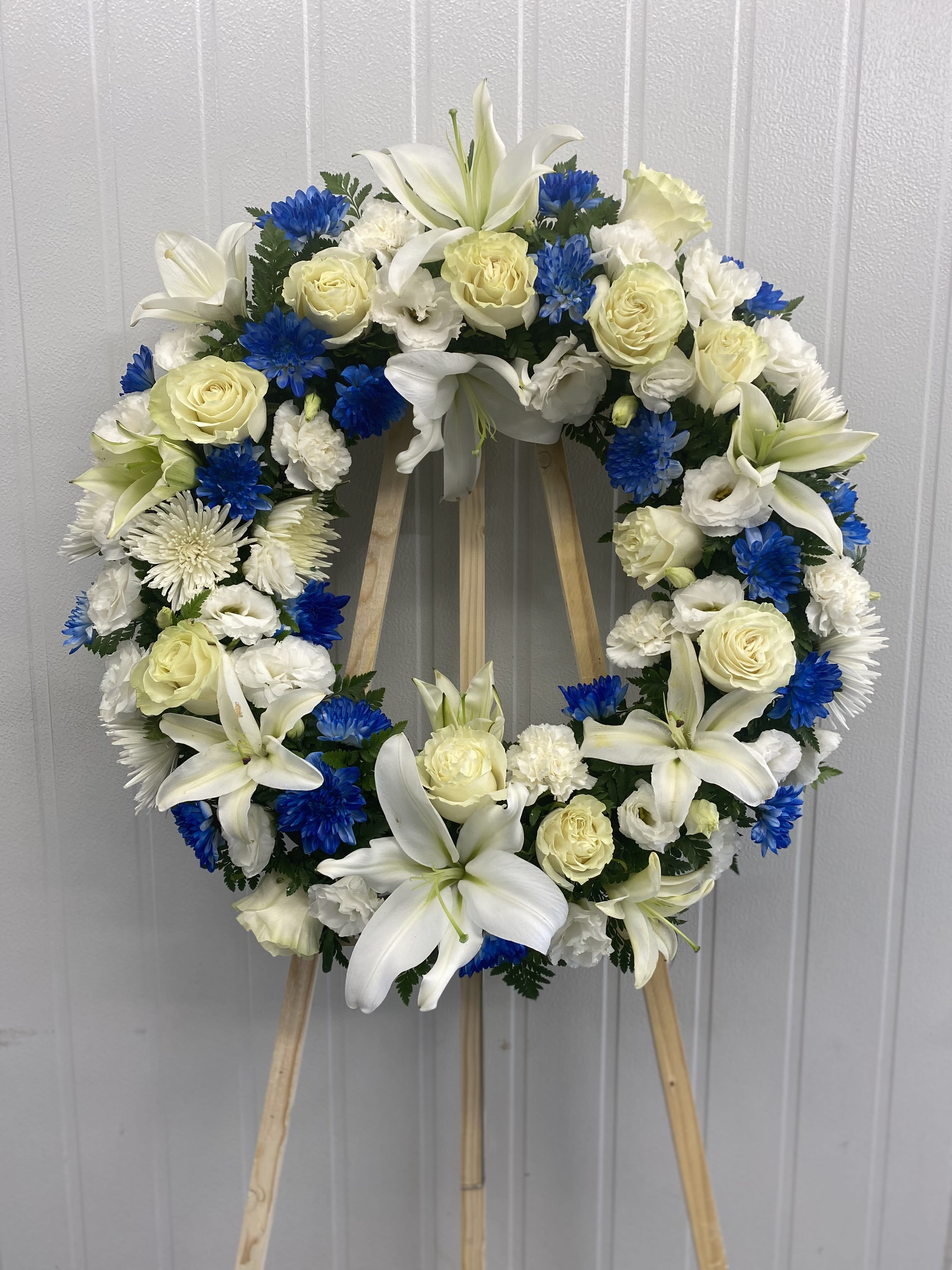 Treasured Tribute Wreath - White Lilies, White Roses , Blue Cushion Pompom, White Spider Chrysanthemums  and Green leaf. 