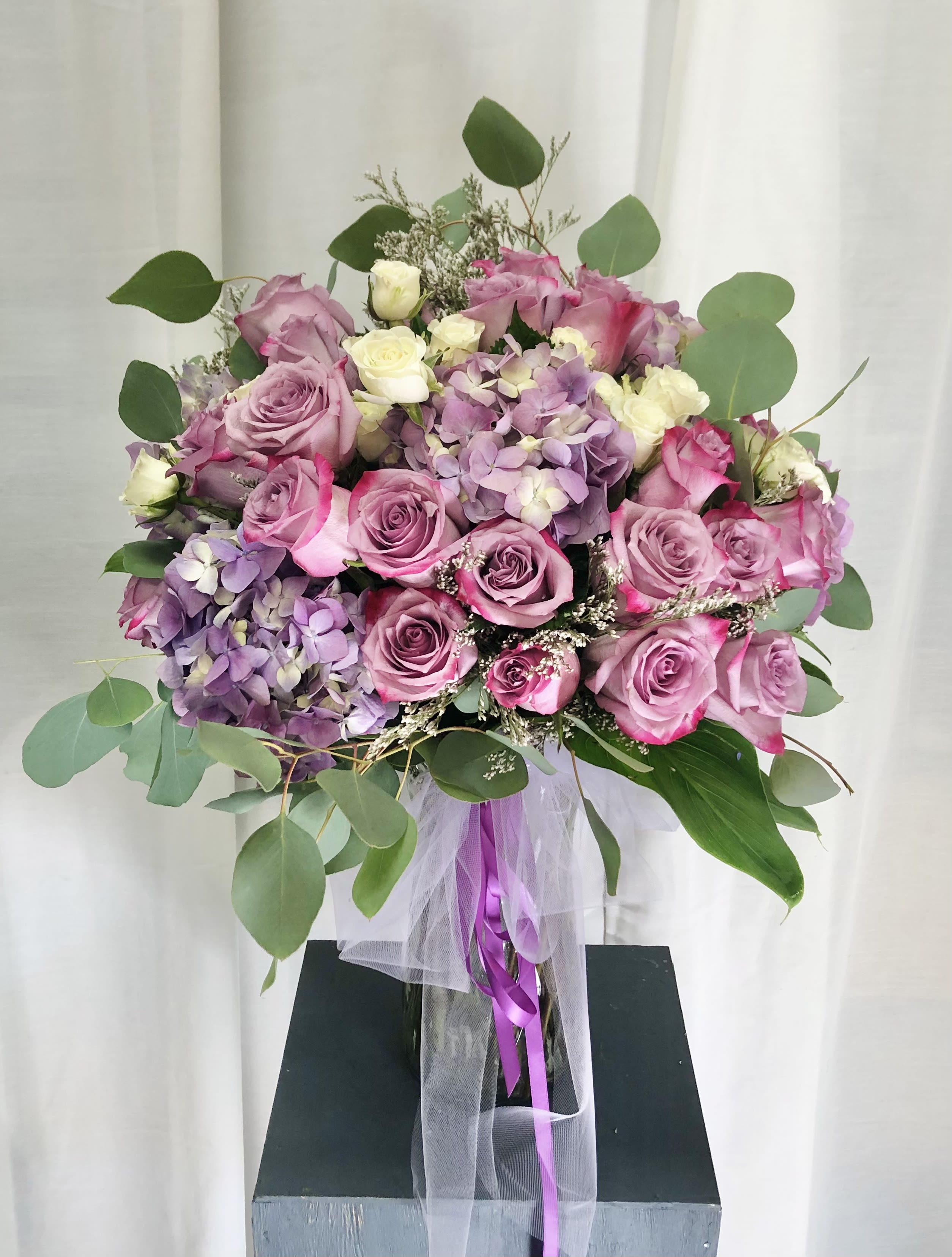 Lavender Dreams - Beautiful arrangement with lilac roses, hydrangeas, white spray roses, and green accents.