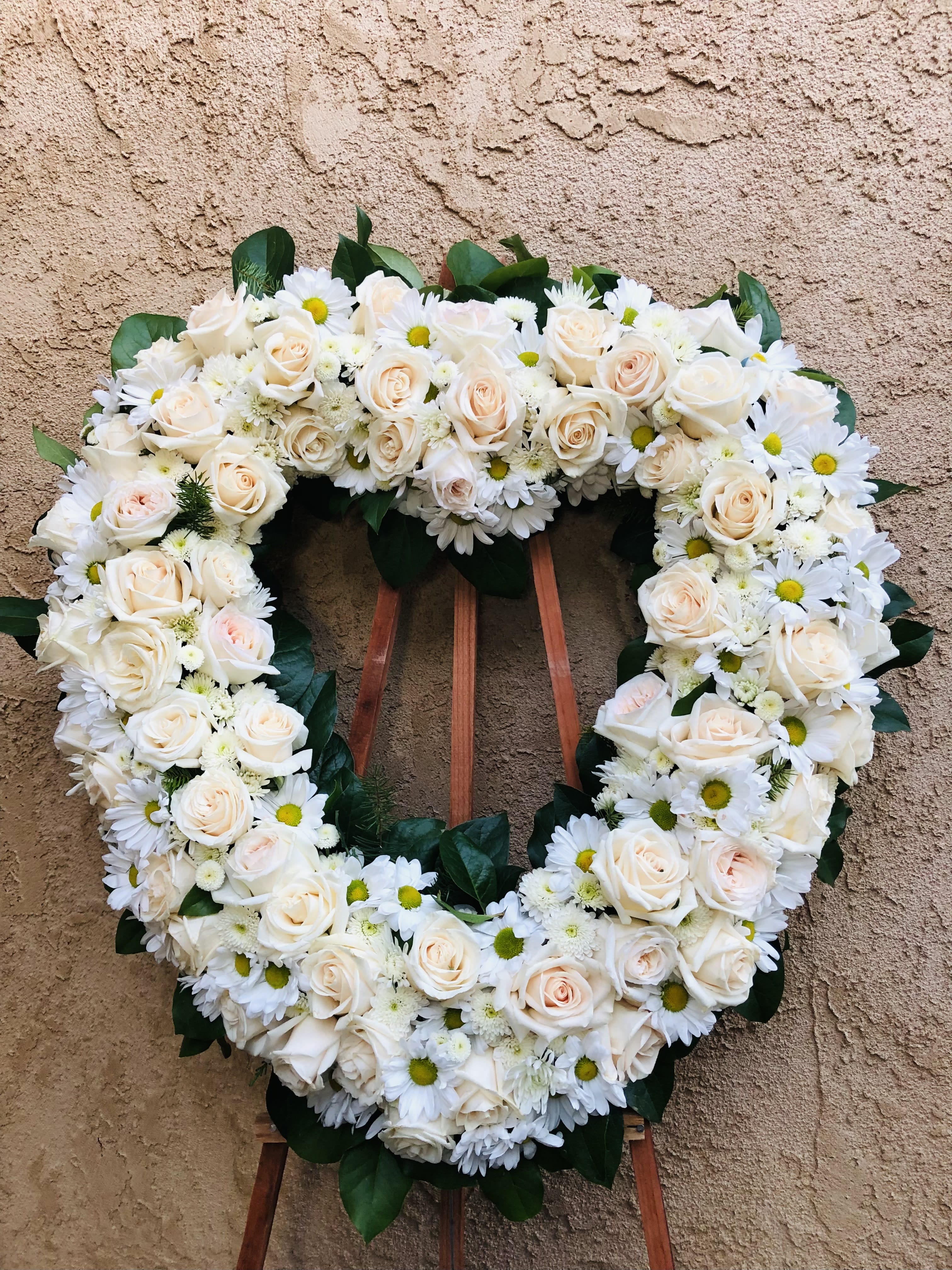 Light Ripples - Elegant standing funeral spray arrangement with mixed whites and green accents. Featuring roses, daises, mini mums, and green accents.