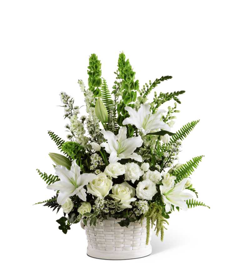 The FTD In Our Thoughts Arrangement - The FTD In Our Thoughts Arrangement is a symbol of pure peace and caring kindness. White roses, tulips, freesia, Oriental lilies, double lisianthus, monte casino asters, and snapdragons, are beautifully offset by bright green Bells of Ireland, ivy vines, and an assortment of lush greens to create an elegant display that conveys your deepest sympathies for their loss. Arrives in a large round whitewash basket.