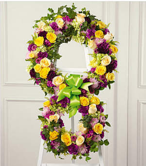 The Eternity™ Standing Easel - The soul's passage into the hereafter is celebrated with this inspiring floral tribute handcrafted by a local  artisan florist to reflect the symbol of &quot;infinity&quot;. The two conjoined wreaths are constructed of yellow roses, fuchsia and purple carnations, fuchsia dianthus, lavender pompons and golden solidago accented with lush greens and trimmed with coordinating ribbon. It is a powerful and lovely statement of faith that is sure to console and comfort all who share your loss.  Your purchase includes a complimentary personalized gift message.