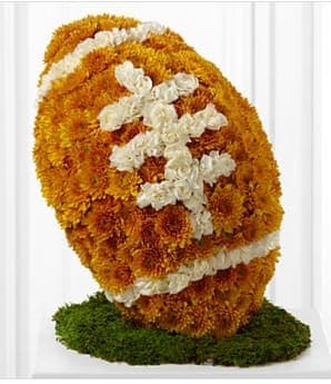  American™ Football Tribute - The FTD® American™ Football is a lovely way to commemorate the life of your loved one. Bronze chrysanthemums and white mini carnations form the shape and likeness of a football standing on a piece of lush green moss, to create a wonderful way to remember the deceased and their favorite pastime at their memorial service. Approximately 15&quot;H x 12&quot;W. Your purchase includes a complimentary personalized gift message.