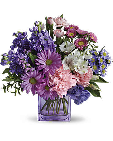 Heart's Delight - A sweetly romantic birthday present or heartfelt gift for a friend, this delightful arrangement pampers her with soft lavenders, deep purples and pretty pinks - not to mention the modern glass cube vase she'll use again and again! Feminine shades of pink, purple and white are seen in flowers including lisianthus, alstroemeria, stock, carnations and daisies.