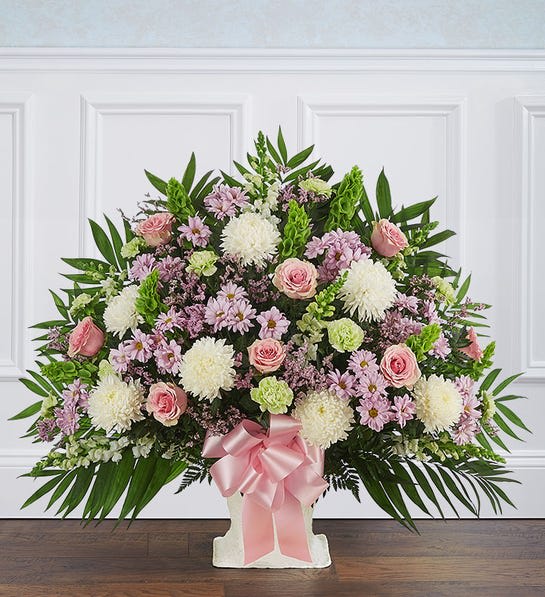 Heartfelt Tribute™ Floor Basket- Pastel - After the loss of a loved one, a heartfelt sentiment goes a long way to show how much you care. Our elegant floor basket arrangement is crafted with soft, soothing pastel blooms, creating a touching tribute to a special loved one, while offering comfort and support when words alone aren’t enough.  One-sided floor basket arrangement with pink roses and limonium, lavender daisy poms, white snapdragons and football mums, lime green carnations, green spider mums, Bells of Ireland; accented with assorted greenery and pink bow Extra large arrangement measures approximately 38&quot;H x 41&quot;W Large arrangement measures approximately 36&quot;H x 40&quot;W Medium arrangement measures approximately 34&quot;H x 36&quot;W Small arrangement measures approximately 32&quot;H x 32&quot;W Appropriate for the funeral home Our florists use only the freshest flowers available, so colors and varieties may vary 