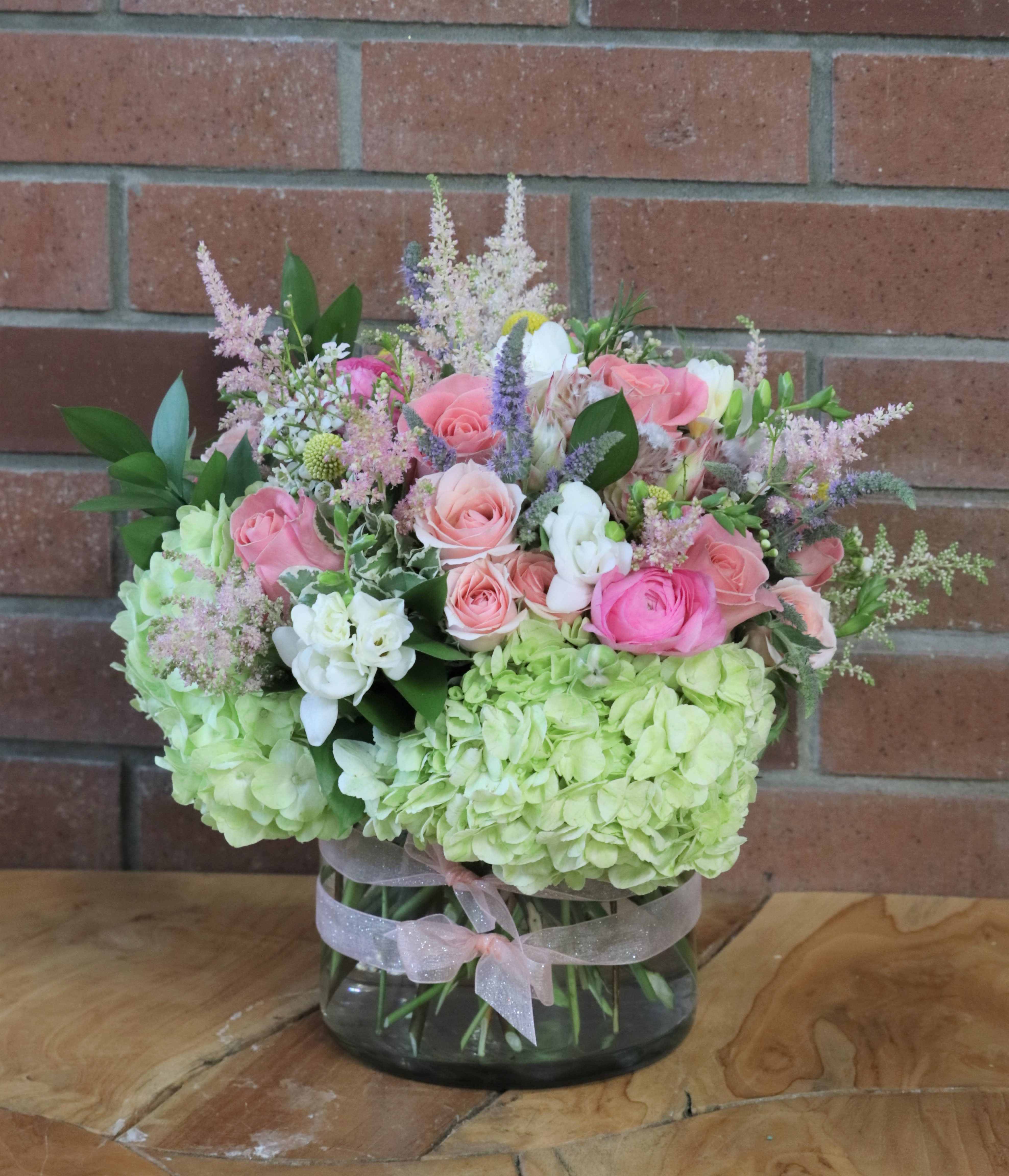 Birthday Blooms Bouquet - Pinks, greens, whites and peache colors in a large cylinder vase accented with ribbons. Peonies, roses, freesia, astilbe, spray roses, tulips, hydrangeas &amp; more