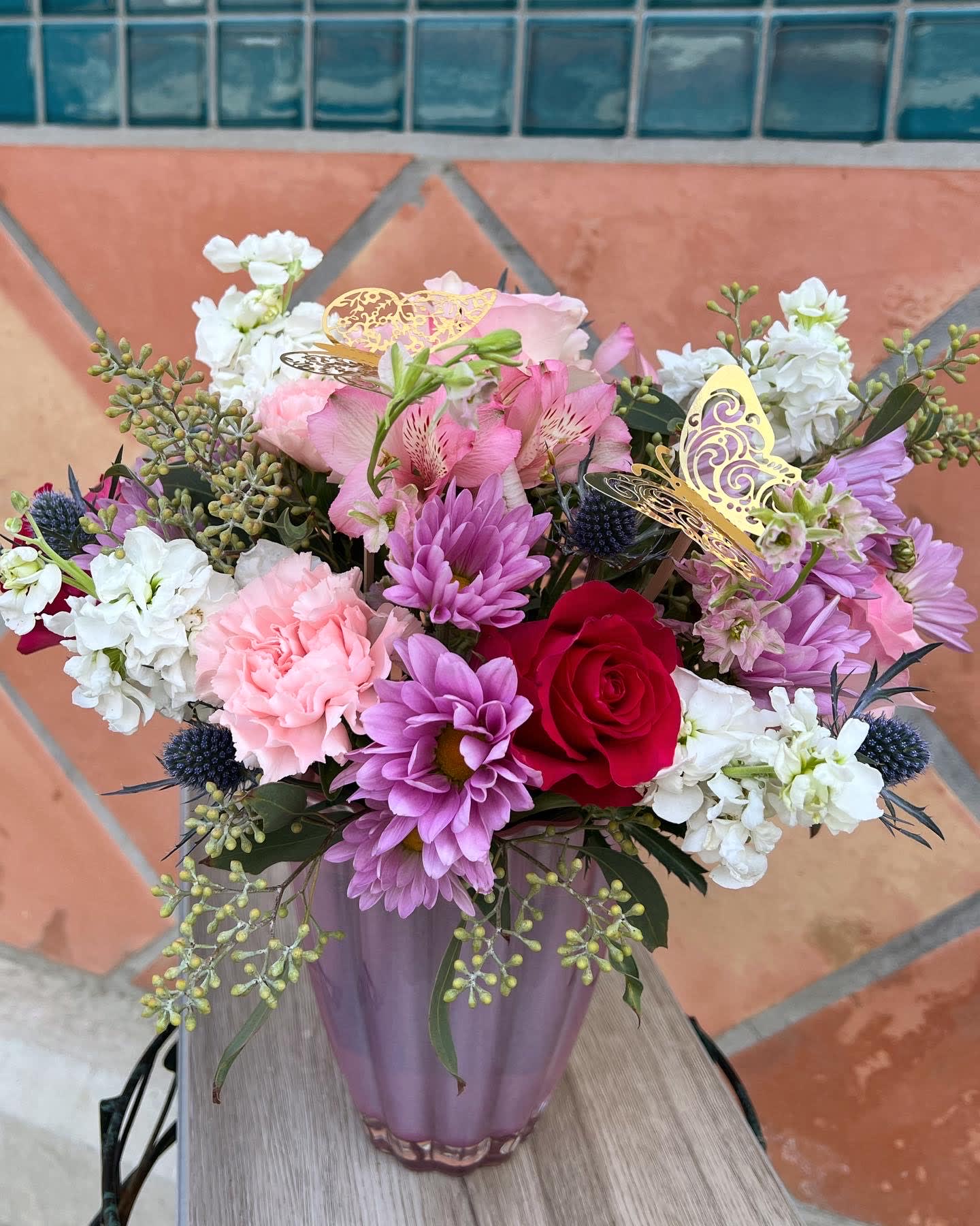 Playful pastel bouquet - lavender, pink, and white flowers are artistically arranged inside an on-trend lavender or pink glass vase.