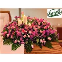 Glowing Remembrance Casket Spray  - Another STUNNING Archer's original. This casket spray has a beautiful mixture of Pink Roses, Purple Daisies, Lavender Buttons, Purple Monte, Pink Wax flower and Baby's Breathe with Leather Leaf and Emerald. 3 Candles Centered. 