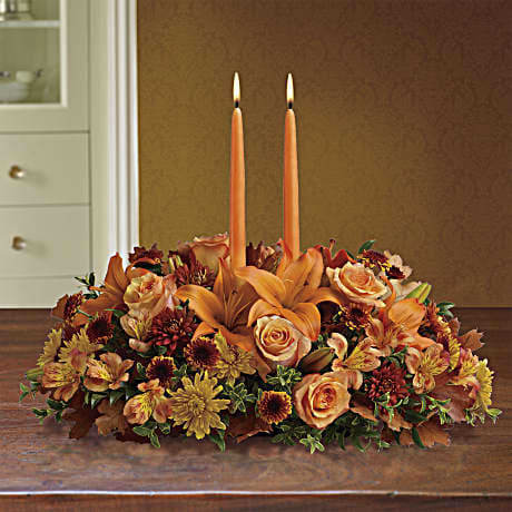 Family Gathering Centerpiece - Graciously gather your family around the warm glow and classic autumn colors of this stunning Thanksgiving centerpiece. A lush variety of burnt orange blooms are gathered under a pair of tall, graceful candles - perfect for decorating your Thanksgiving dinner table, entryway or hearth.