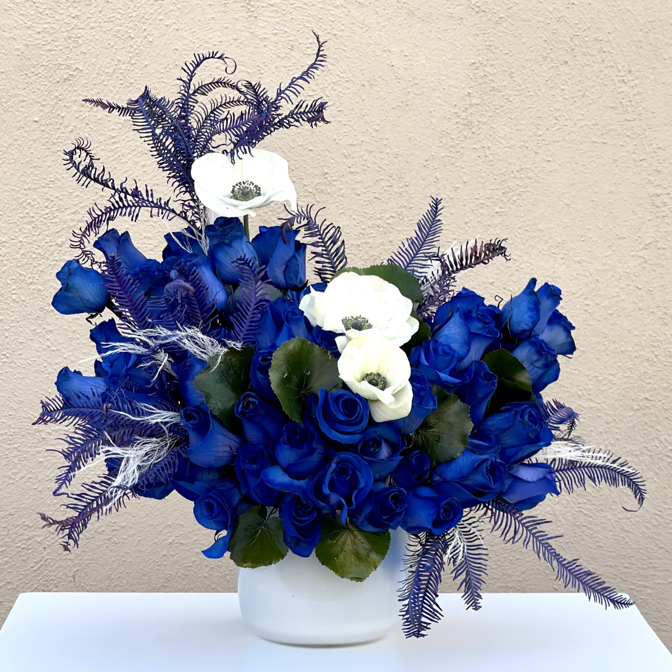 Singing the Blues - This modern blue arrangement featuring over 50 blooms of blue roses and accented with white Anemonies in a matte white vase.