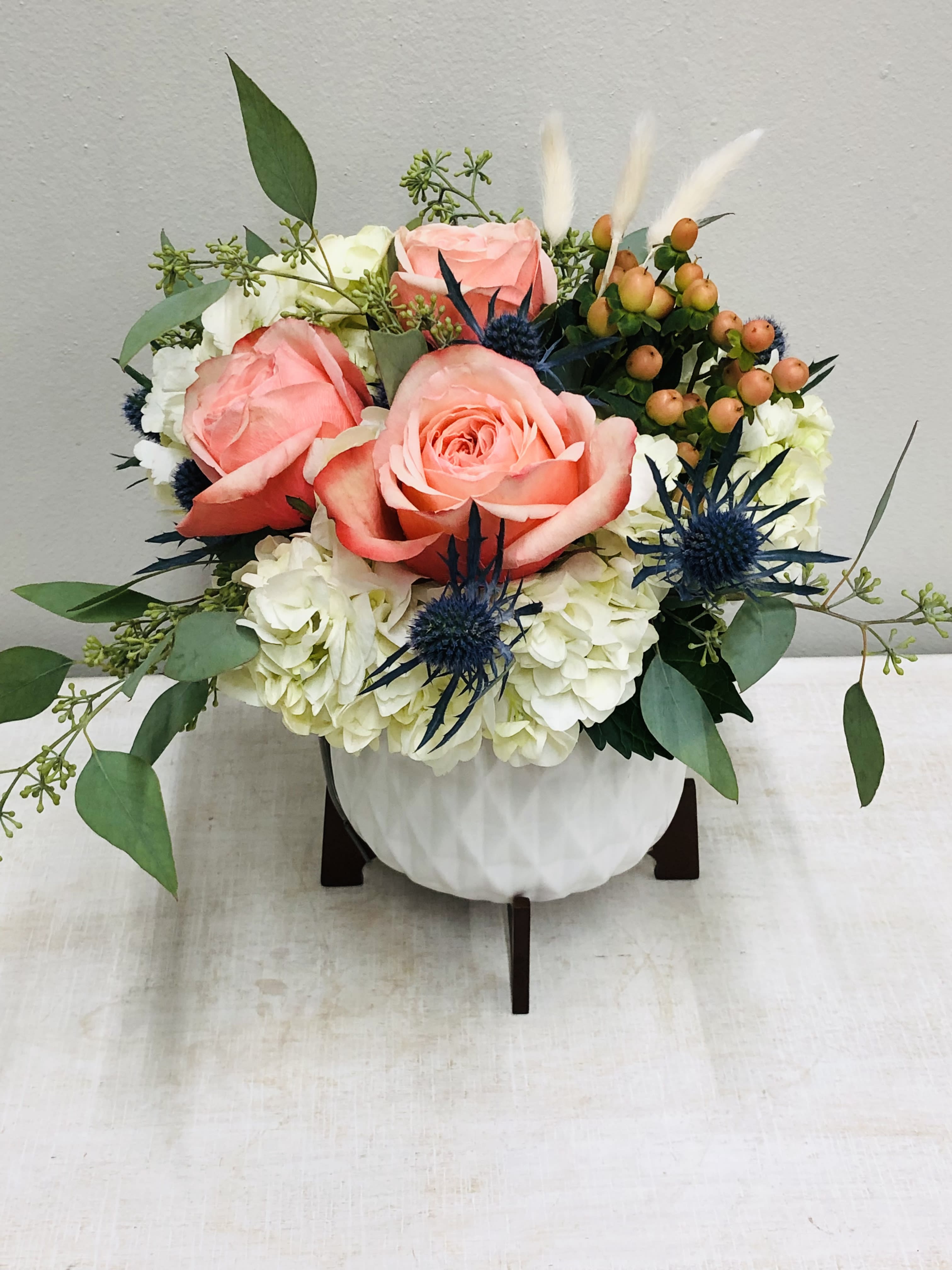 Mini Mod  - Modern white ceramic with wood stand is filled with hydrangeas, roses, thistle, hypericum and seasonal greenery. It’s the perfect trendy gift.    Flowers and colors may vary depending on availability/season. Local delivery ONLY for container.