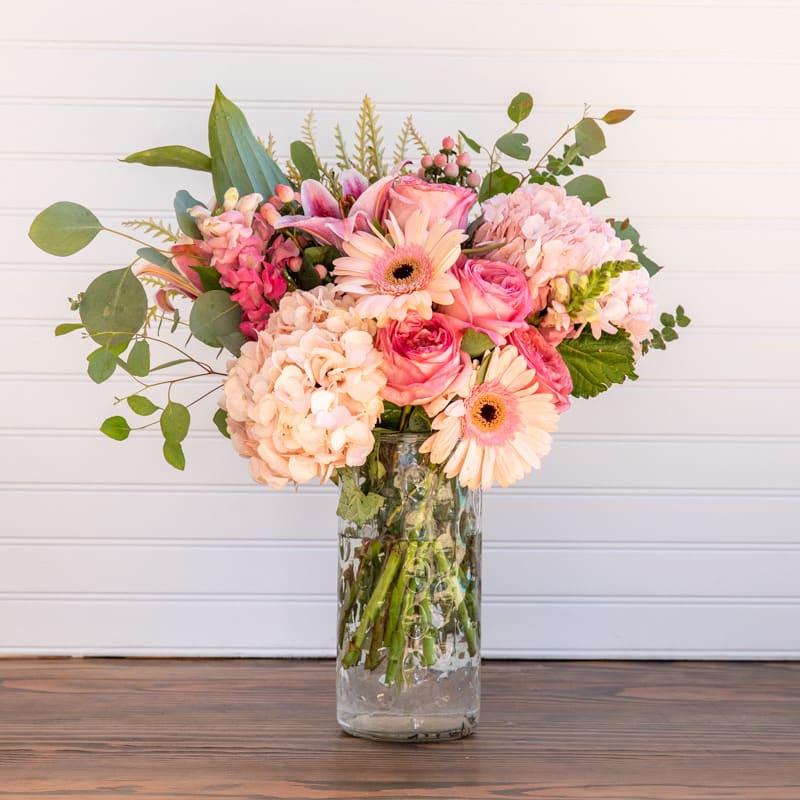 Pretty in Pink! - This is what you'll hear when the flowers arrive...&quot;They're so lovely!&quot; When you are thinking of a vase of mixed flowers... this is it. A clear vase full of a beautiful blur of colors and styles that will brighten up any space. A whole lot of flowers, plenty of greenery, and not a whole lot of symmetry makes this one a fun one!