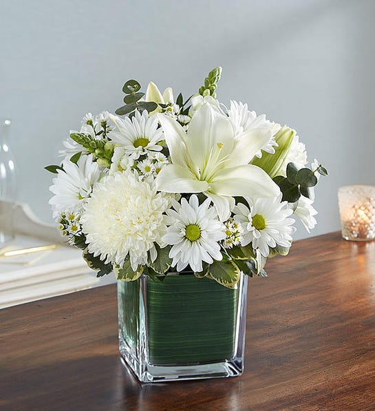 Healing Tears™ All White - There is an innocence to all souls that is evoked in an expression of pure white. Our sympathy arrangement of angelic white roses, lilies, mums, daisy poms and more, expertly arranged in a clear glass cube lined with a Ti leaf ribbon, makes for an exquisite gesture of comfort and healing.  Arrangement of white roses, Asiatic lilies, football mums, snapdragon, daisy poms and monte casino; accented with fresh greenery Artistically designed by our florists in a classic clear glass cube lined with a Ti leaf ribbon; vase measures 5&quot;H x 5&quot;D Large arrangement measures approximately 11&quot;H x 11&quot;L Medium arrangement measures approximately 10&quot;H x 10&quot;L Small arrangement does not include roses and measures approximately 9&quot;H x 9&quot;L Perfect gift for delivery to the homes of family members or friends Our florists hand-design each arrangement, so colors, varieties, and container may vary due to local availability Lilies may arrive in bud form and will open to full beauty over the next 2-3 days  Colors can be customized. Please leave specific notes in the instruction panel at checkout. 