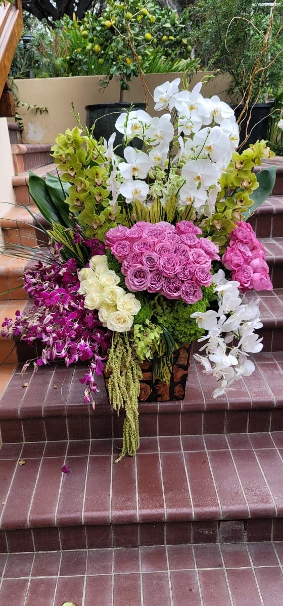 Home Is Where The Heart Is - A grand arrangement, sure to delight, filled with roses, orchids and other flowers of the season.