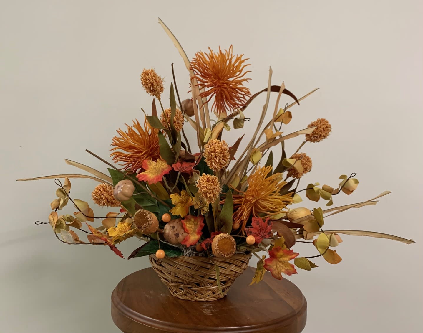 Fall Is In the Air Arrangement - Orange basket with silk flowers in shades of orange and purple.