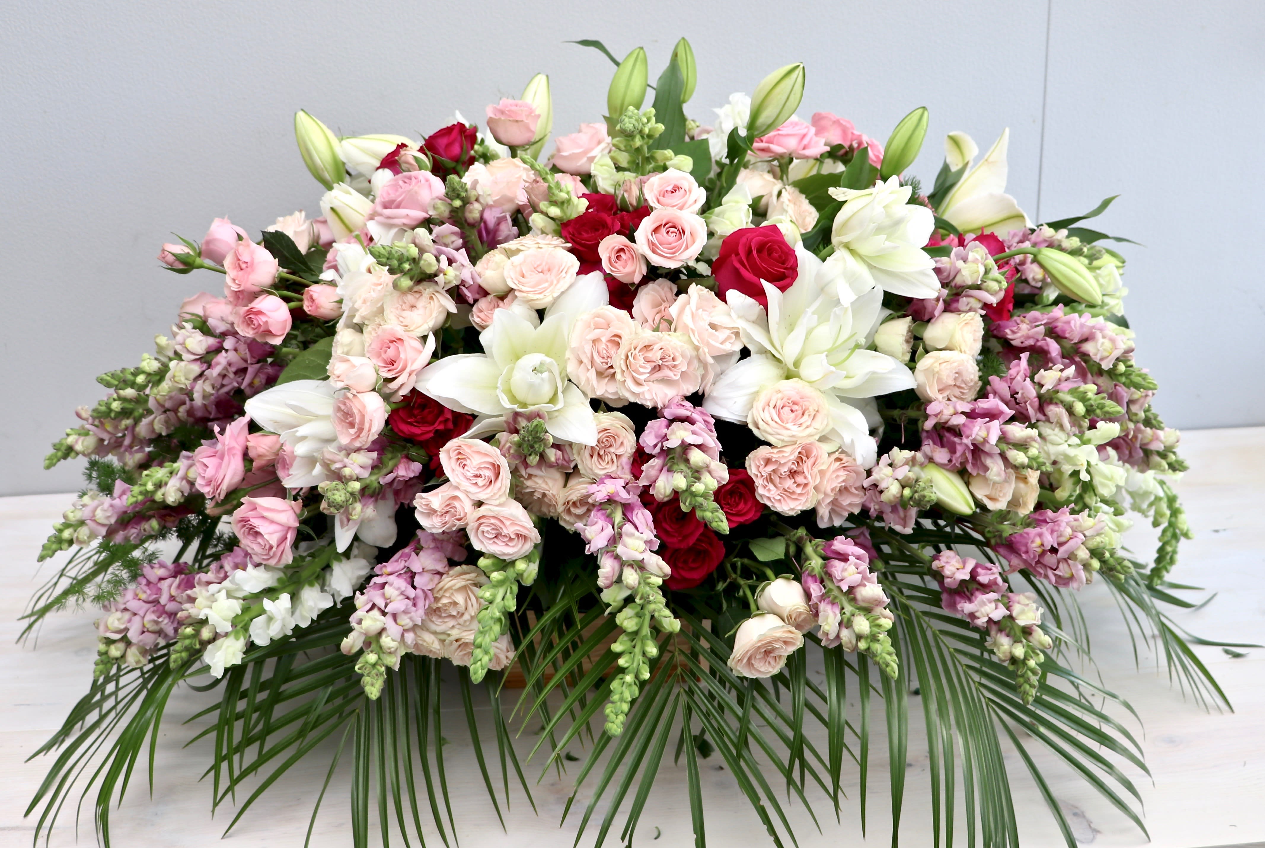 Pinks and White Casket - My Glendale Florist  - This casket arrangement is made with different hues of pink and white roses, stargazer lilies, and fragrant seasonal greens.