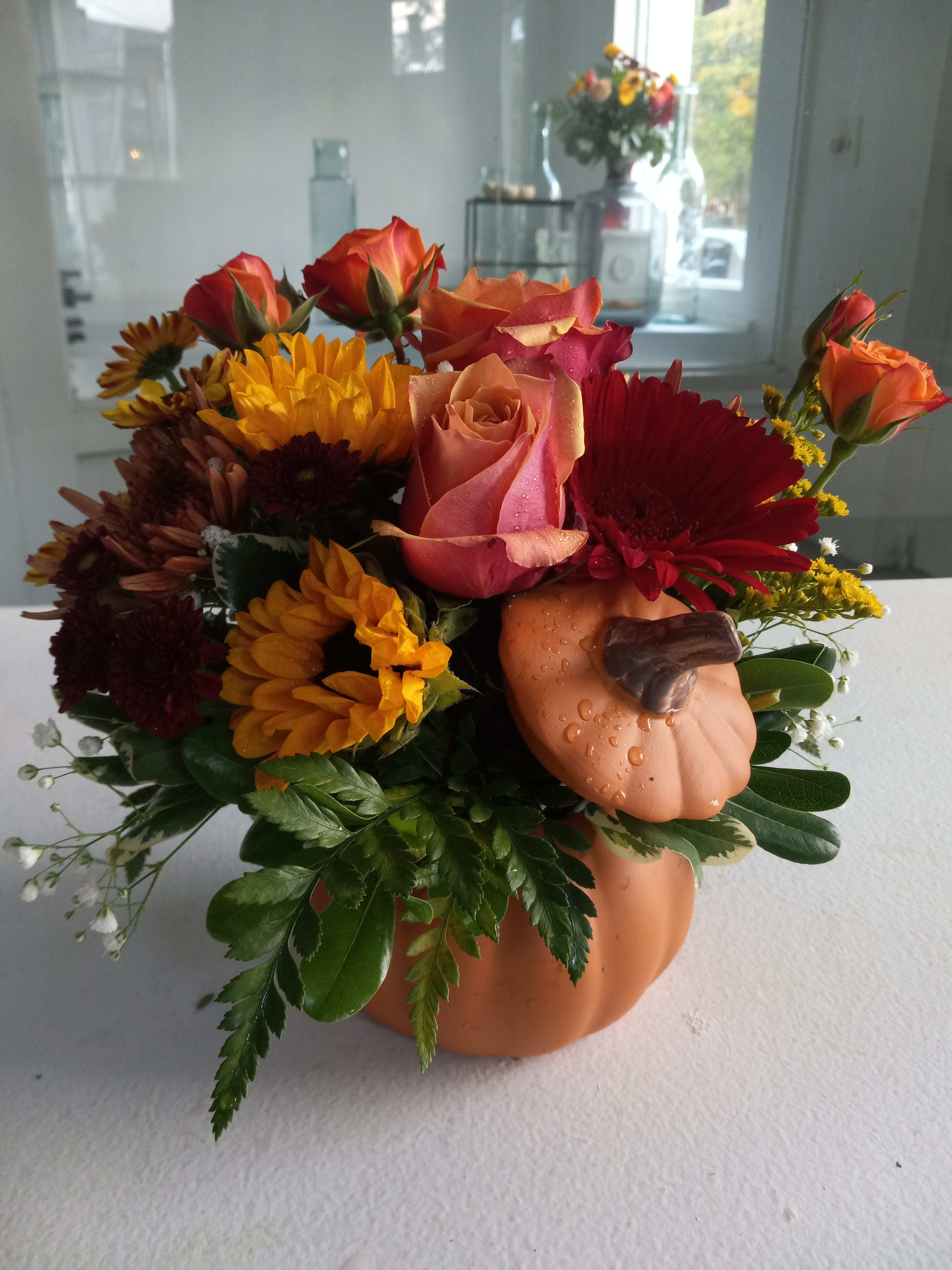 Pumpkin spice - Orange pumpkin container with bright seasonal flowers.