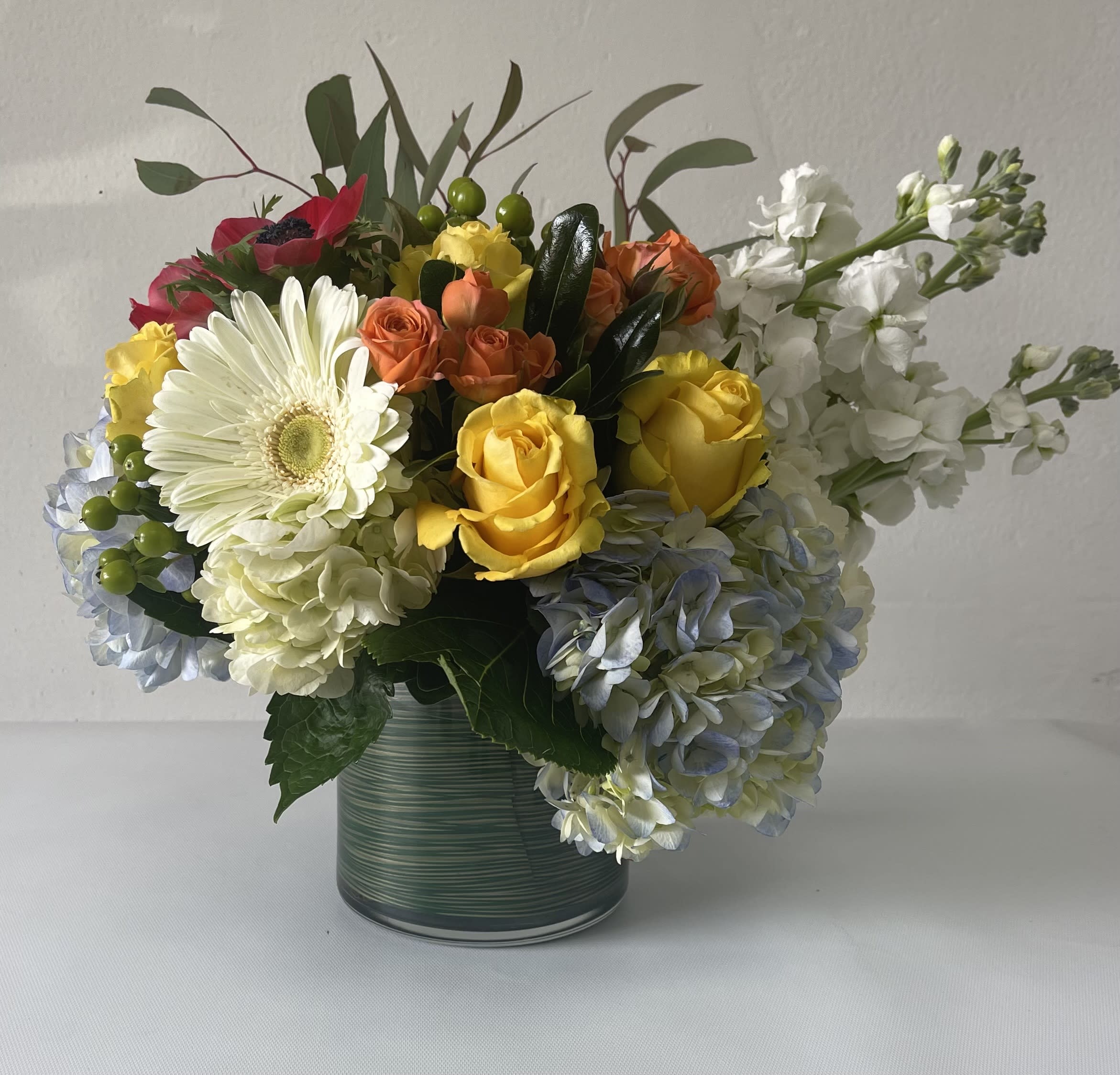 Toco el Cielo Toco el Cielo - Mix of Color with flowers such as Gerbs, Hyndrageas, stock and roses arranged in a cilinder.