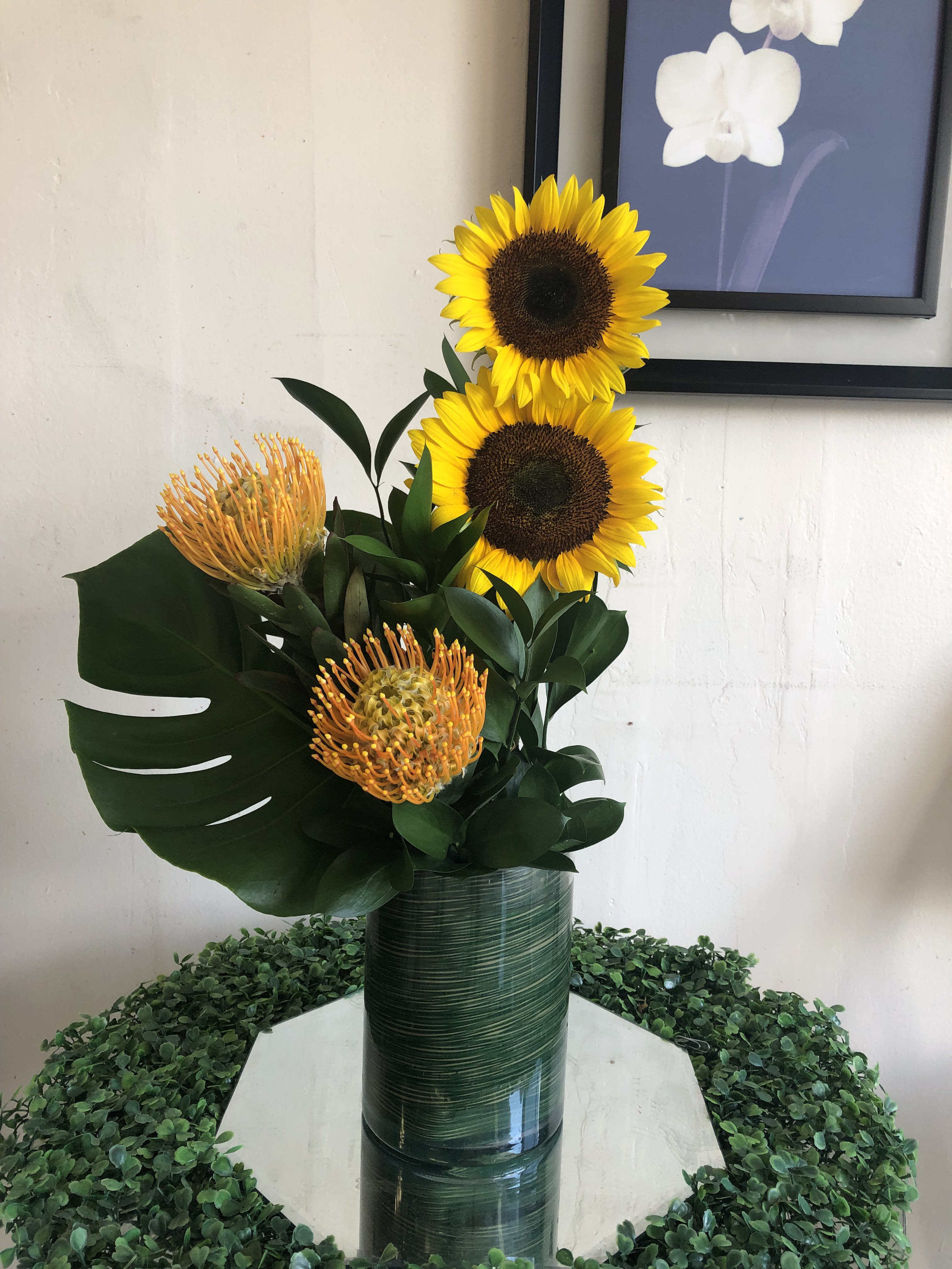 Fireball - This sunny bouquet is sure to brighten anyone's day! Fresh sunflowers in a cilinder vase with a teleaf inside and some mosteras to add elagance to this perfect arrangement. 