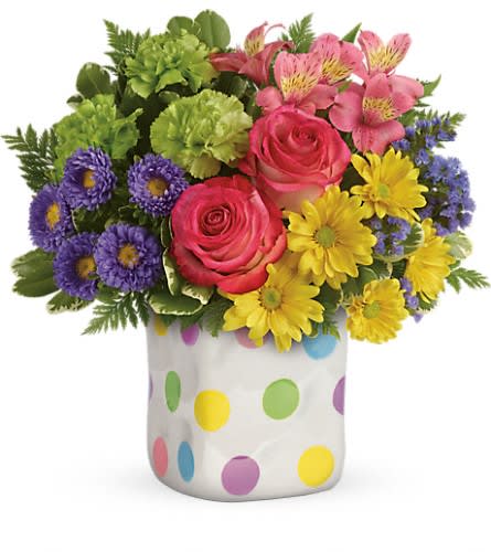 Teleflora's Happy Dots Bouquet - by Collene's Crafts-N-Flowers - Dots what friends are for! Brighten a friend or loved one's spring day with this delightfully dotty gift. Filled with a happy mix of pink green purple and yellow blooms this charming ceramic vase has a fun hand-thrown look and a playful spirit that makes everyone smile! This happy arrangement includes hot pink roses pink alstroemeria green carnations lavender matsumoto asters yellow daisy spray chrysanthemums purple sinuata statice variegated pittosporum and leatherleaf fern. Delivered in a Happy Dots cube.Approximately 13 1/2&quot; W x 12 1/2&quot; H Orientation: One-Sided As Shown : T16E300ADeluxe : T16E300BPremium : T16E300C