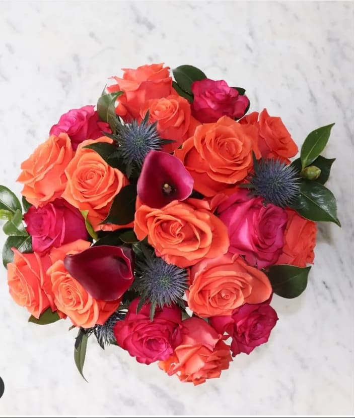 Be Mine Be Mine - A gorgeous arrangement of orange and hot pink roses, with a touch of dark red callas and greenery in a clear vase