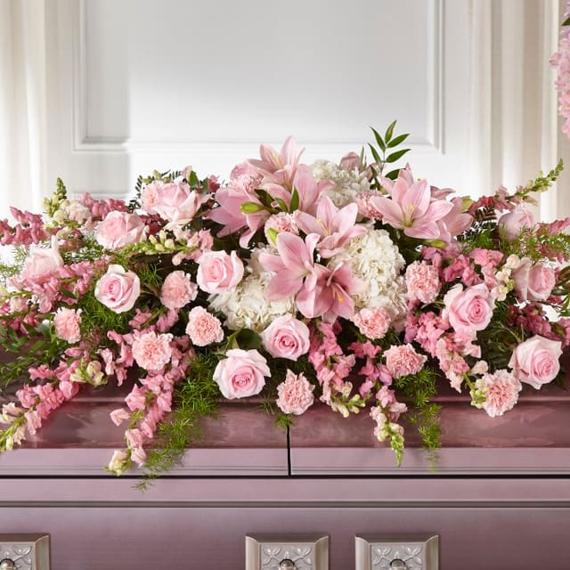 Life &amp; Remembrance Casket Spray - Pink flowers are comforting, dainty and add a touch of grace to your messages of sympathy. Our Life &amp; Remembrance™ Casket Spray beautifully celebrates the life of a loved one. Each arrangement is handcrafted by a local florist with white hydrangea, pink lilies, roses and carnations. Casket spray is approximately 12&quot;H x 51&quot;W