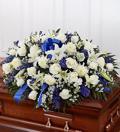 Blue &amp; White  Half Casket Cover - Honor a life so beautifully lived with a proud display of blue and white blooms. Our half casket cover, crafted with care and artistry by our expert florists with blue delphinium, white roses, and accented with a blue satin ribbon, is an unforgettable way to commemorate a lifetime of loving devotion. 