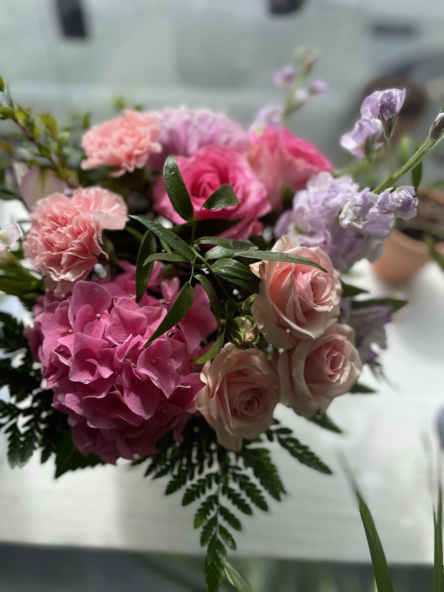 Blushing  - This beautiful arrangement has a pink spray rose, pink hydrangea, lavender stock pink carnations, pink roses, and lavender mums.