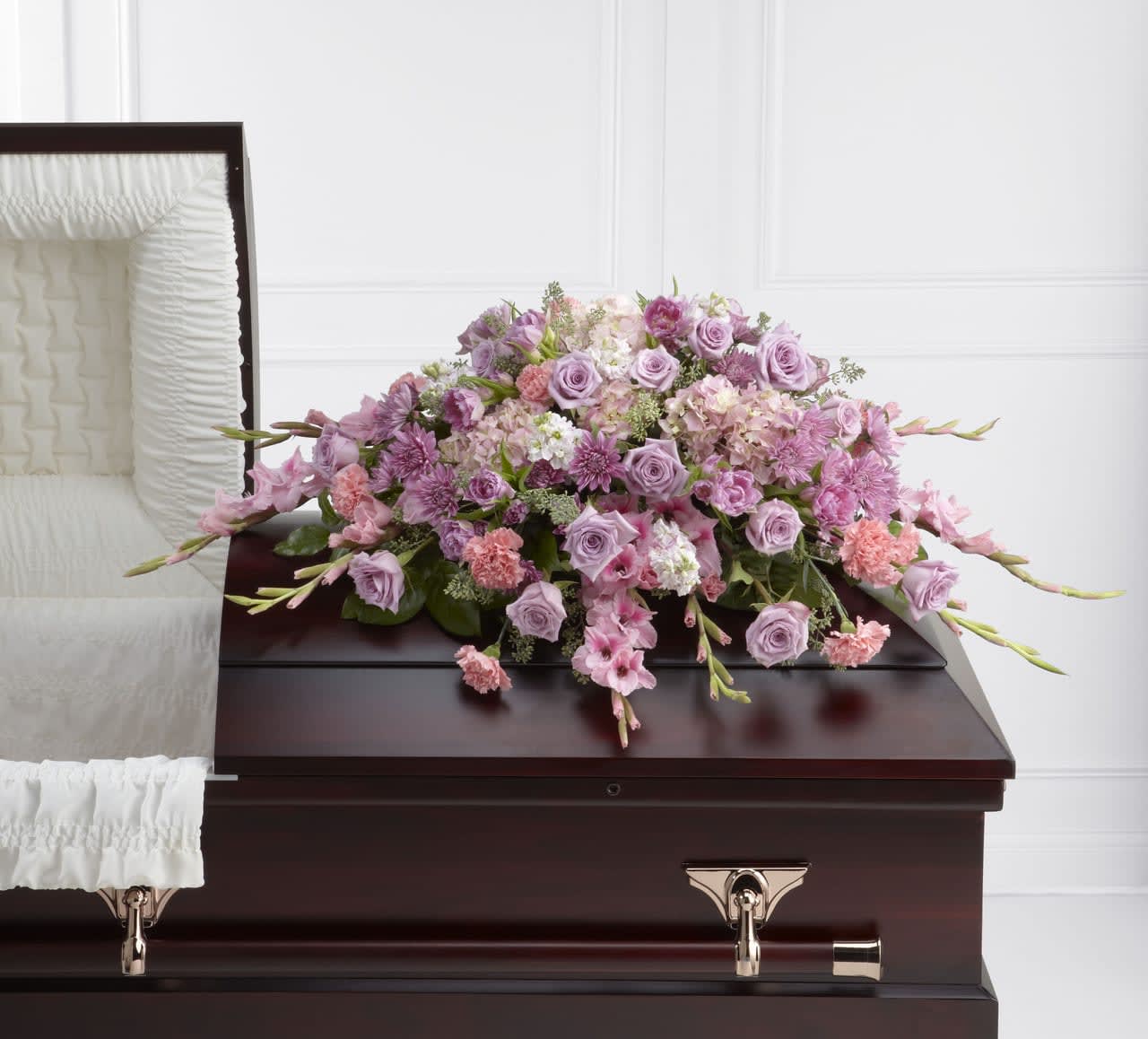 TLSP The Immorata Casket Spray - The Immorata Casket Spray offers soft beauty and blushing comfort to honor the life of the deceased. Lavender roses, chrysanthemums and parrot tulips are elegantly arranged amongst pink carnations, gladiolus, stock, hydrangea and lush greens to create a presentation, intended to bedeck the top of the casket, that evokes sweet memories of your loved one for their final farewell service. Approximately 38&quot;W x 28&quot;D.  Your purchase includes a complimentary personalized gift message.