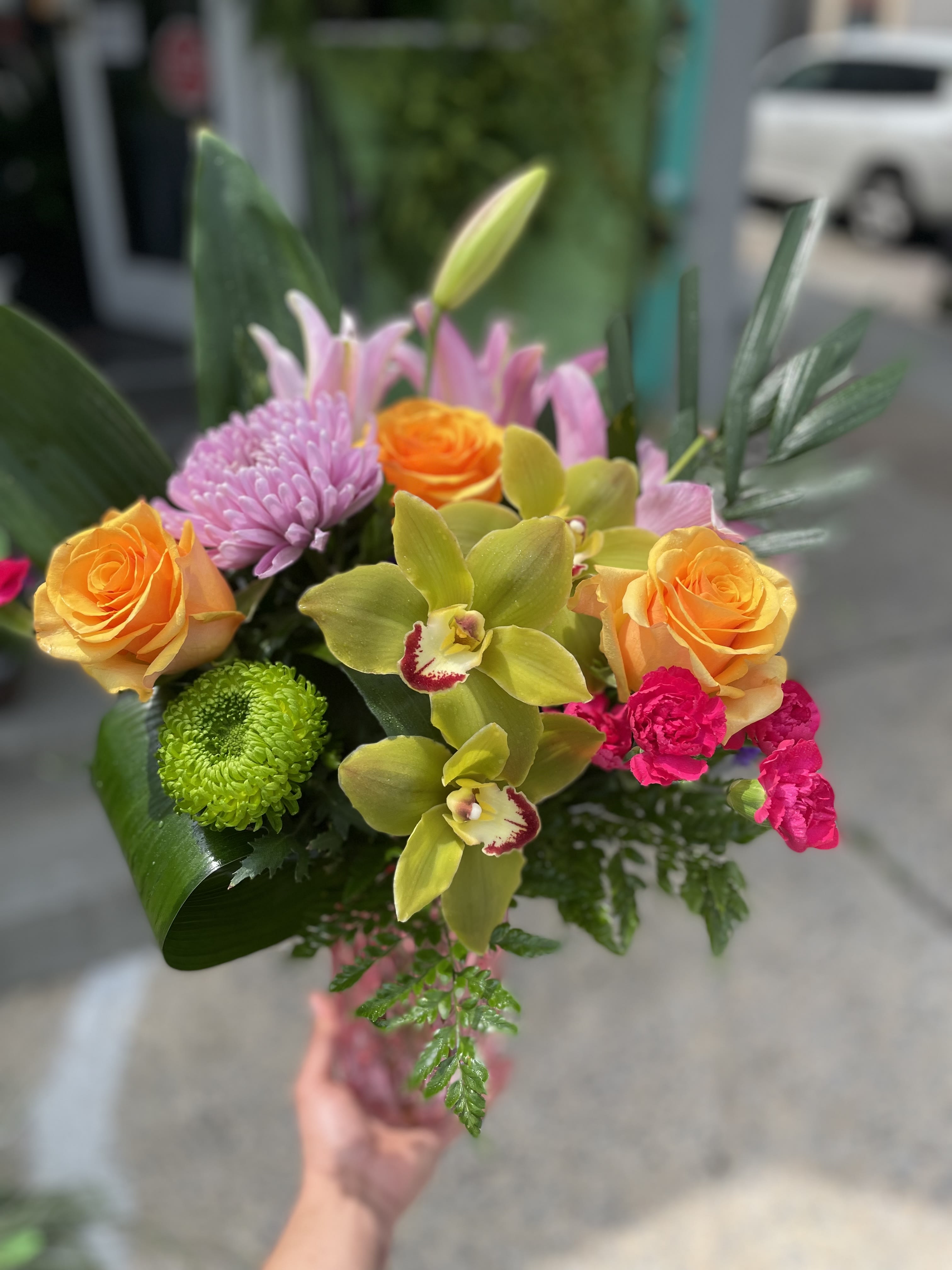 Reflexión  - This beautiful arrangement has yellow roses, green orchid, pink lily’s, green and lavender mums, pink carnations, and fresh greens.