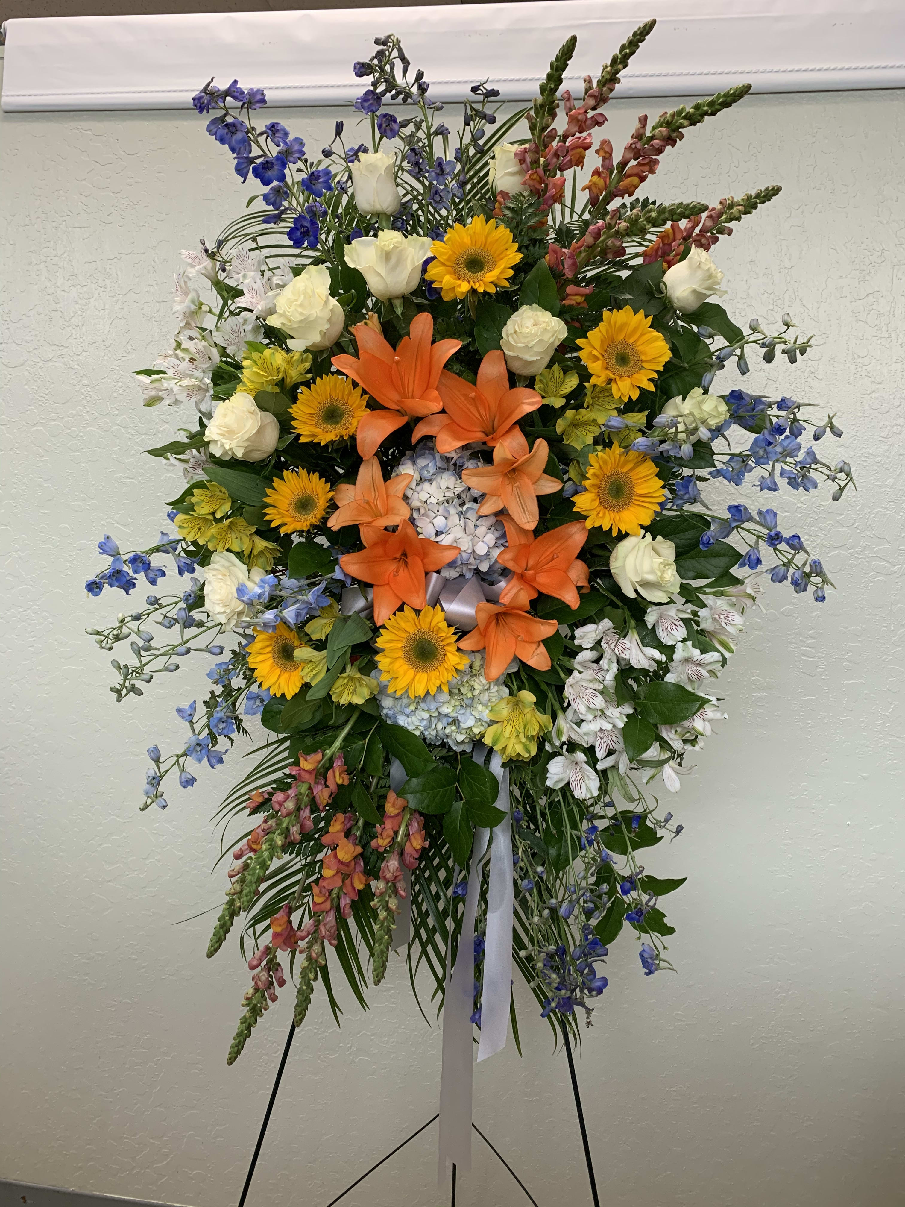 SS#22 Colorful Serenity Spray SS#22 Colorful Serenity Spray - This standing spray features blue hydrangea, blue delphiniums, orange asiatic lilies, orange snapdragons, white roses, white and yellow alstroemeria, mini sunflowers, and mix greens and lemon leaf. The arrangement is approximately 48" H and 24" W. Standard (as shown)