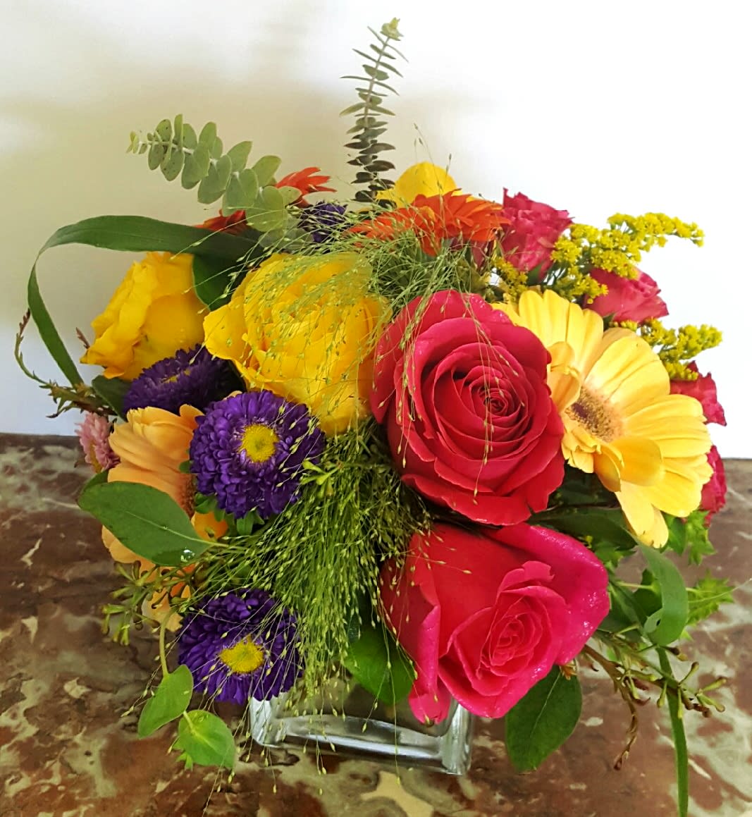 Spring Explosion  - What a way to bring in the spring season!  Pink and yellow Roses brighten this beautiful bouquet filled with mulit-colored Gerbera Daisies, Matsumoto Asters, Cushions and multi-colored Spray Roses or similar flowers accented with Explosion Grass and Spiral Eucalyptus or similar foliage.