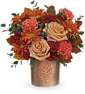 Lovely Leaves - This autumn arrangement includes light orange roses, orange carnations, miniature maroon carnations, bronze daisy spray chrysanthemums, parvifolia eucalyptus and brown copper beech. Delivered in Teleflora's Lovely Leaves Cylinder. Approximately 12 1/2&quot; W x 12 1/2&quot; H Teleflora's Lovely Leaves Bouquet stunning fall bouquet certainly leaves them breathless! Brimming with lush roses and blooms, this copper-finished metal vase features a cutout leaf design that later glows as a candle holder.