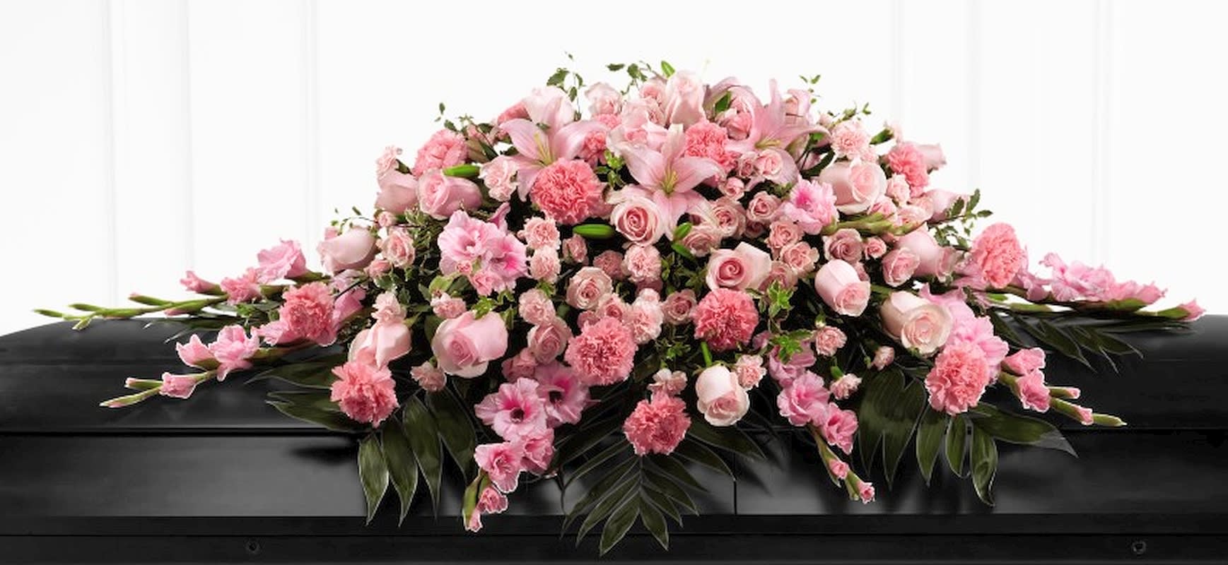 Sweetly Rest Casket Spray Sweetly Rest Casket Spray - This is a wonderful way to commemorate a life abundant in beauty and love. Blushing pink roses, spray roses, carnations, gladiolus, mini carnations and Asiatic lilies are elegantly arranged amongst an assortment of lush greens to create a sophisticated display meant to bedeck the open casket or the top of their closed casket as well at the final memorial service.