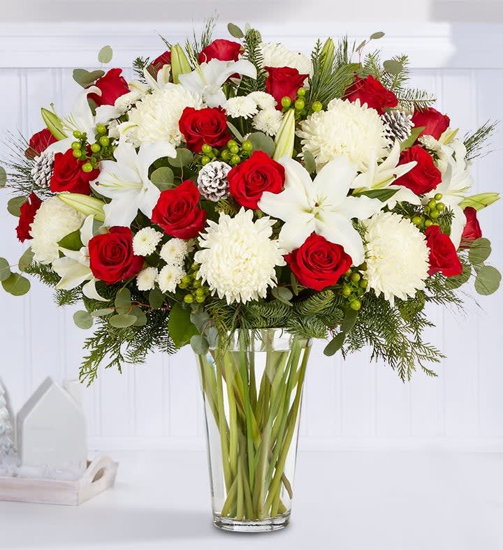 Garden of Grandeur for Holiday Garden of Grandeur for Holiday - All-around arrangement with red roses, white Oriental lilies, football mums and button poms, green hypericum; accented with silver dollar eucalyptus, assorted Christmas greens and glittered pinecones Artistically designed in a clear glass vase Extra large arrangement measures approximately 33"H x 20"W Large arrangement measures approximately 31"H x 19"W Medium arrangement measures approximately 28"H x 19"W Small arrangement measures approximately 27H x 18"W Our florists hand-design each arrangement, so colors, varieties and container may vary due to local availability To ensure lasting beauty, Oriental lilies may arrive in bud form and will fully bloom over the next few days