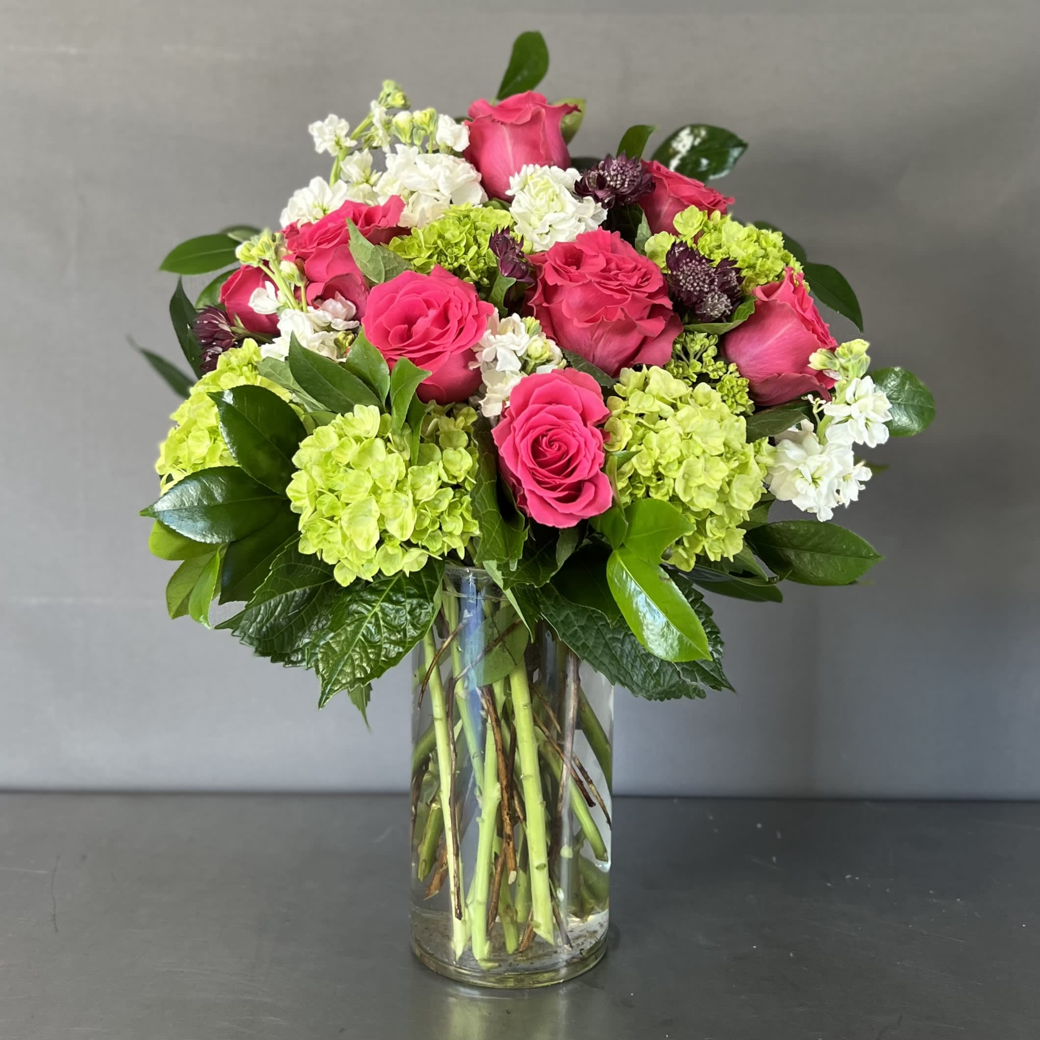 EVERYDAY PINK - Roses, hydrangeas, and seasonal flowers are arranged in a glass vase. 