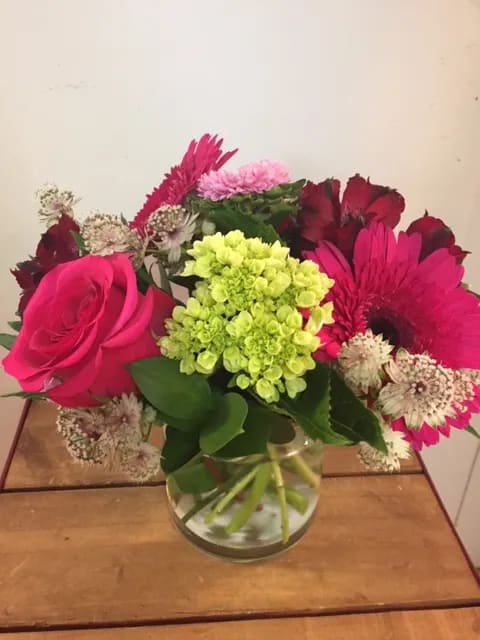 Hot Pink Garden - A sweet mix of hot pink blooms including roses, gerbera daisies and alstromeria presented in a simple cropped style perfect for a desk or side table.