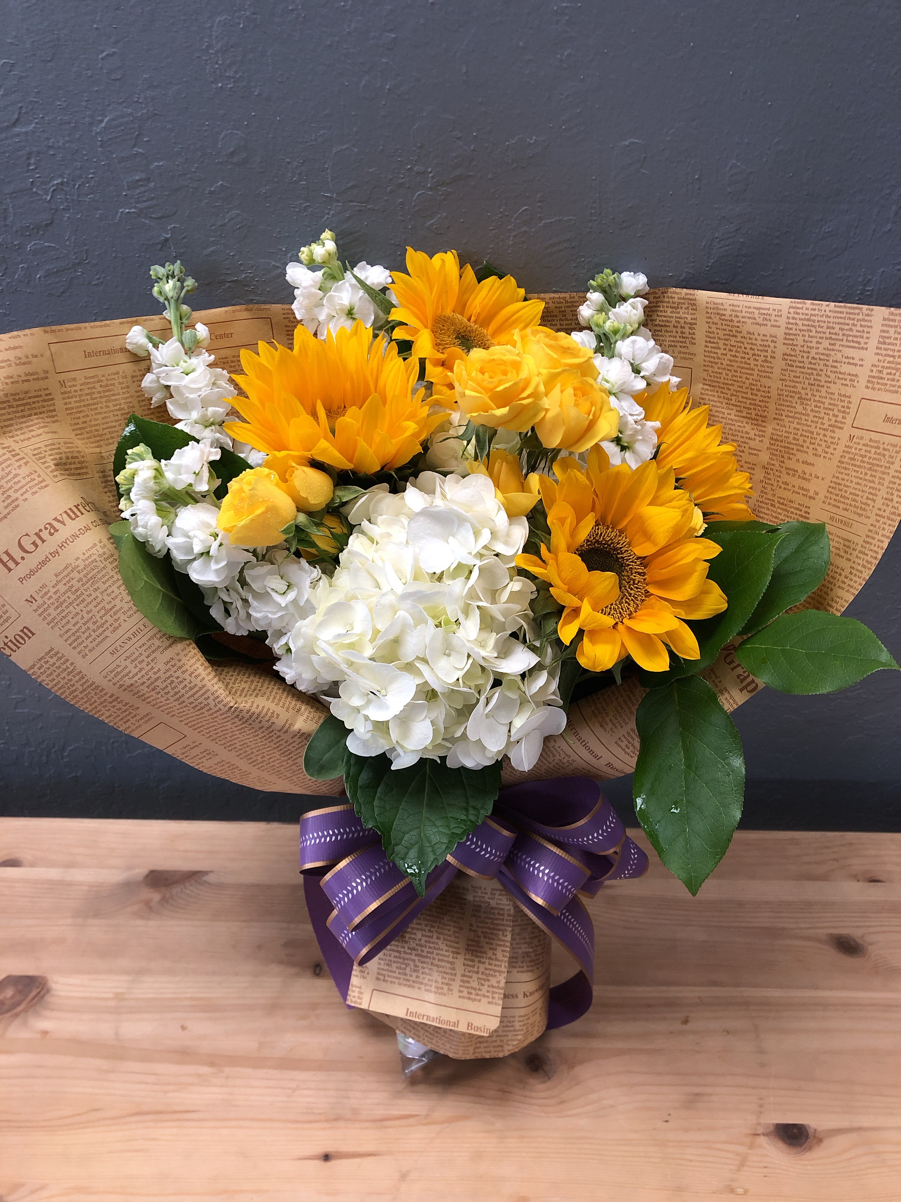 Sunny Delight Wrapped Bouquet - This delightful bouquet will bring out smiles with its sunflowers, roses, stocks, and hydrangeas. 