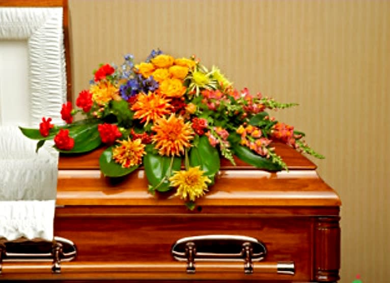 Graceful Garden Casket Spray - This graceful casket spray of bright blossoms in shades of red, orange, blue and yellow, arranged against a backdrop of greenery, will celebrate a life well-lived.