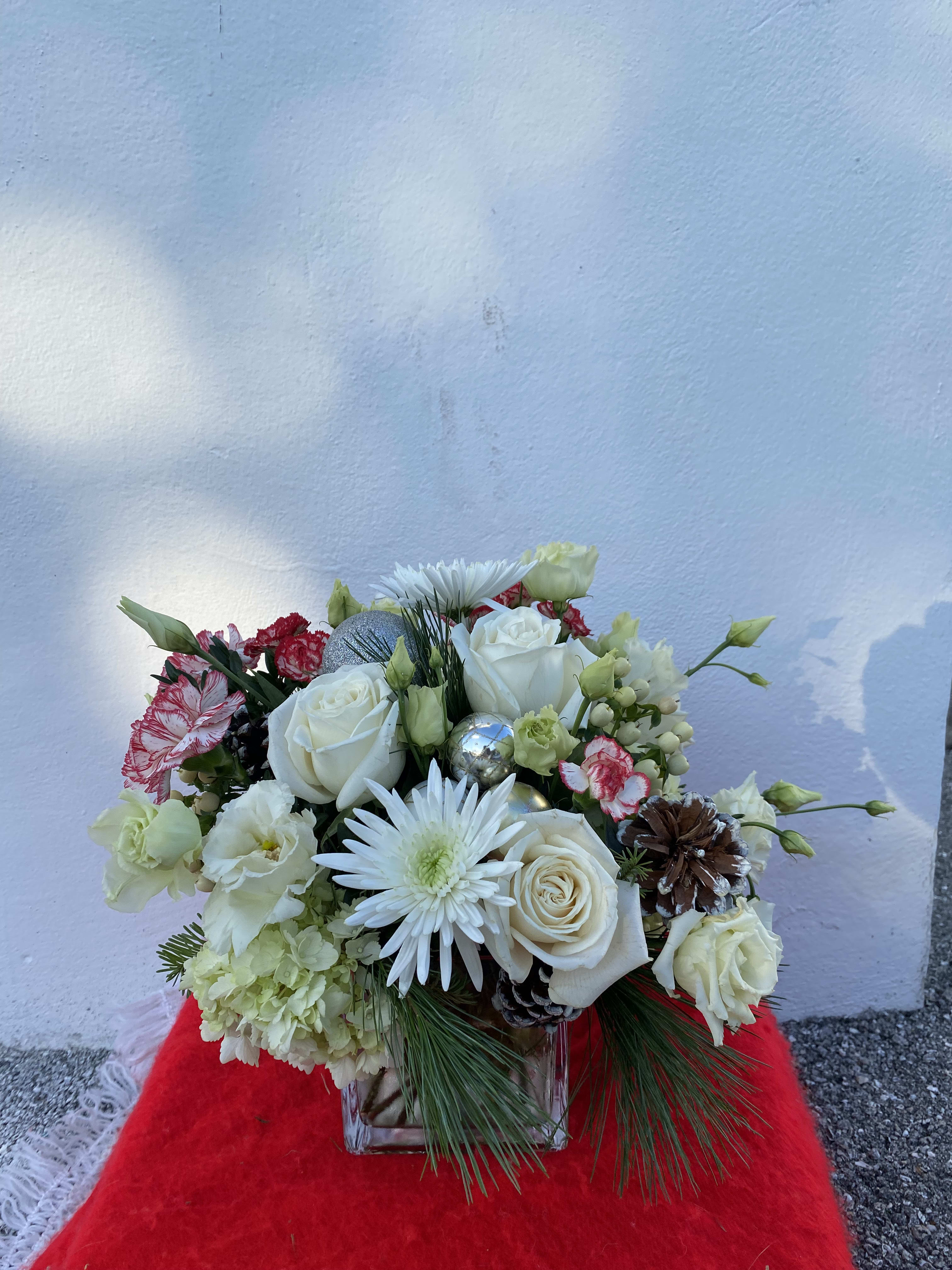 CFH109 CFH109 - A low compact style arrangement with christmas greens, roses, hydrangea and other flowers in holiday colors with pinecones and other accents perfect for the dining room table or coffee table.