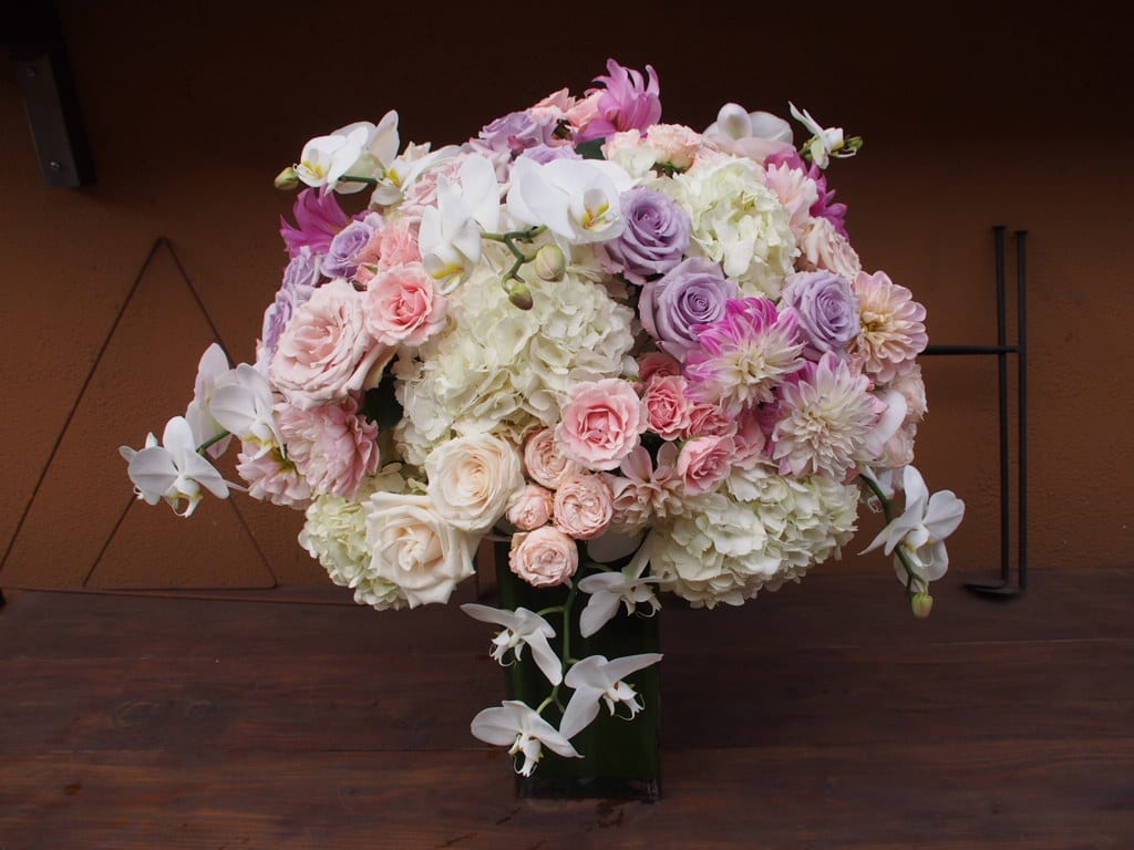 Jubliant Jubliant - Tall vase with lush of flowers, pastel pinks and whites. Touches of lavender flowers and phalenopsis orchids.