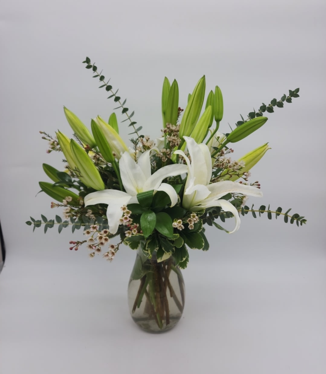 Written in the Stars - Elegant white lilies and pretty white waxflower stems are exquisitely arranged in a vase that's reminiscent of a star-filled sky. It really is a wish come true.  