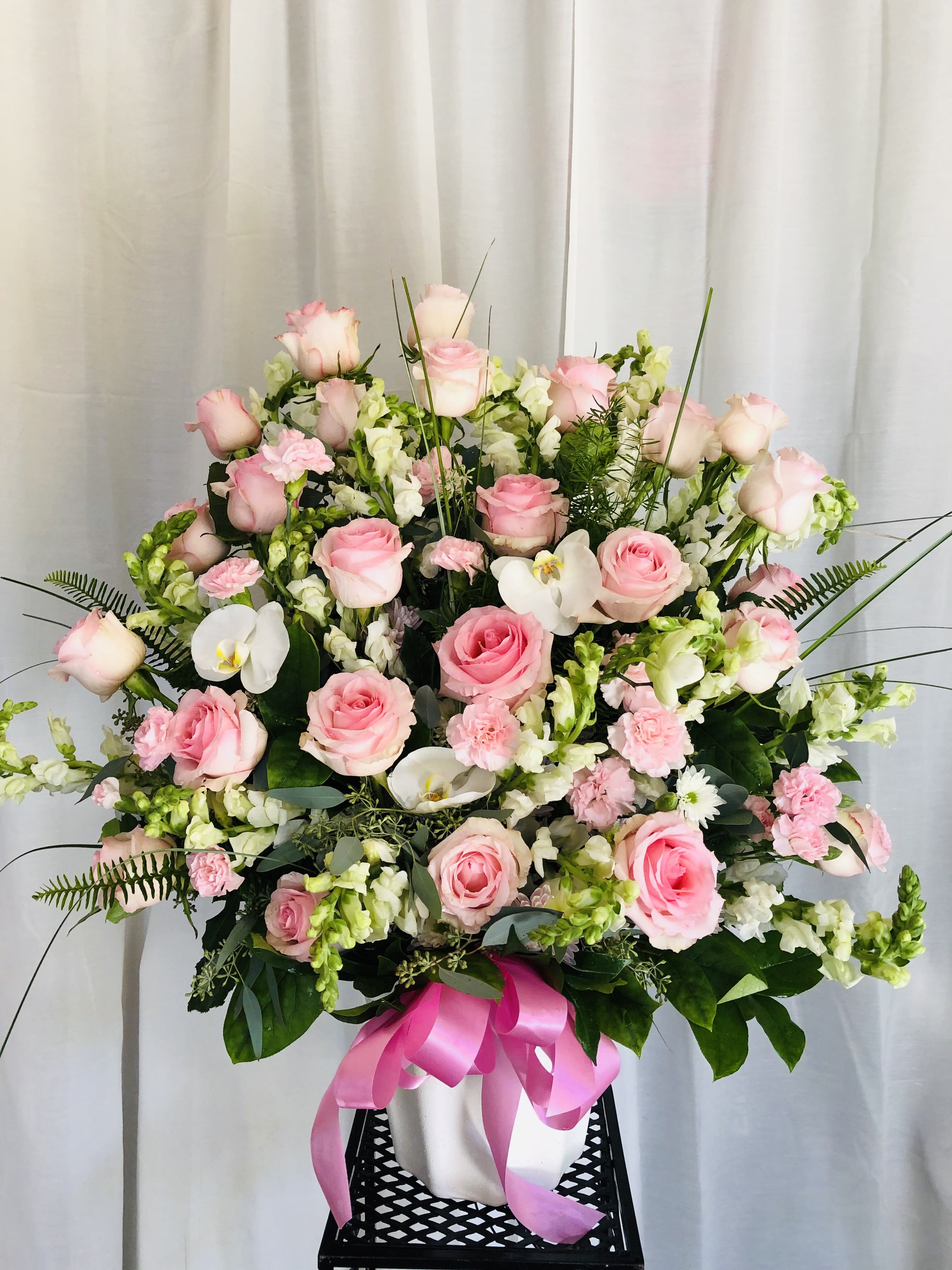 Pink Prize - Beautiful pink and white vase arrangement featuring roses, carnations, fillers, orchids, and leaf accents.