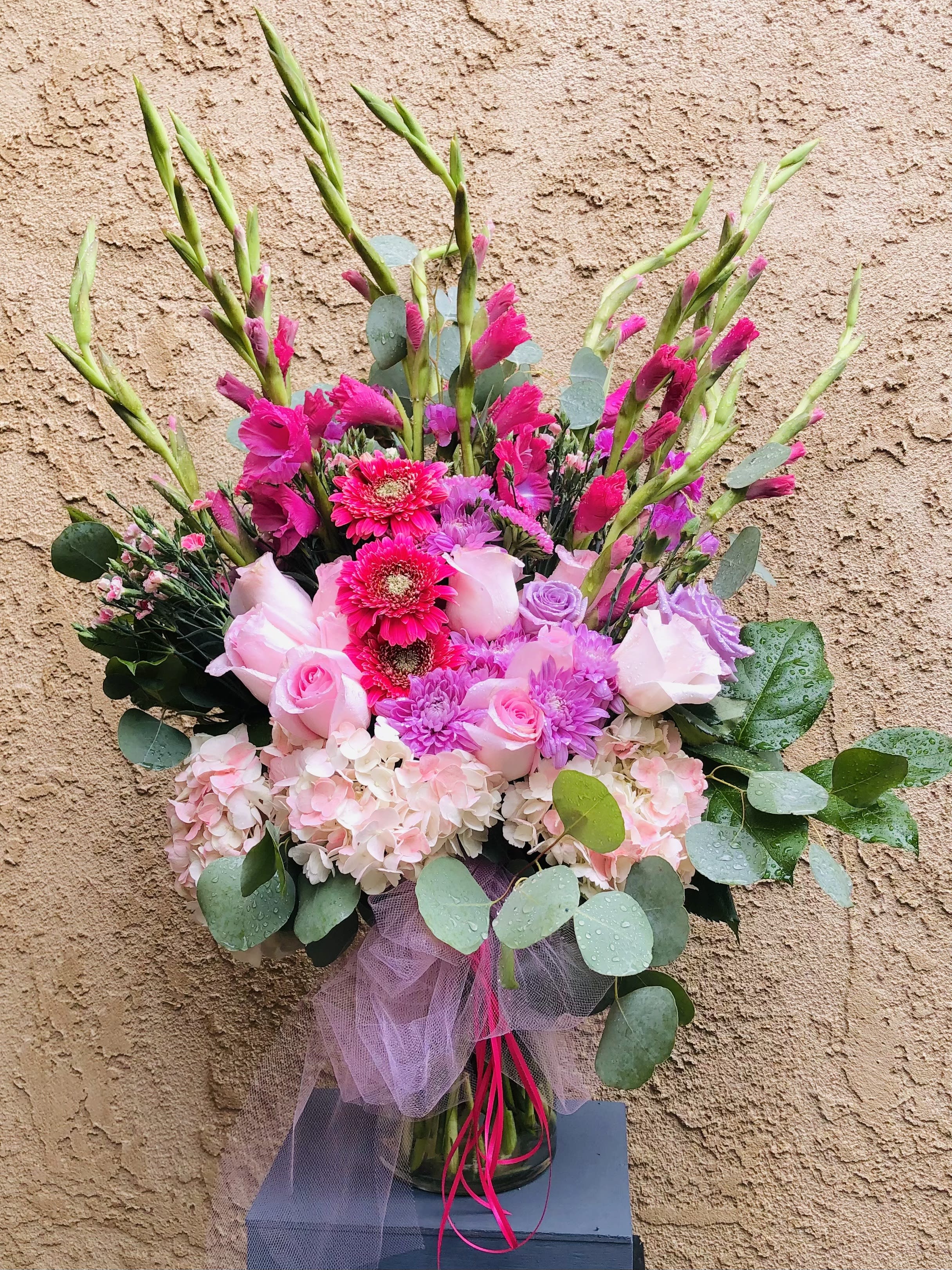Lush Life - Beautiful vibrant pink vase arrangment featuring gladiolus, roses, daises, hydrangeas, mums, and green leaf accents.