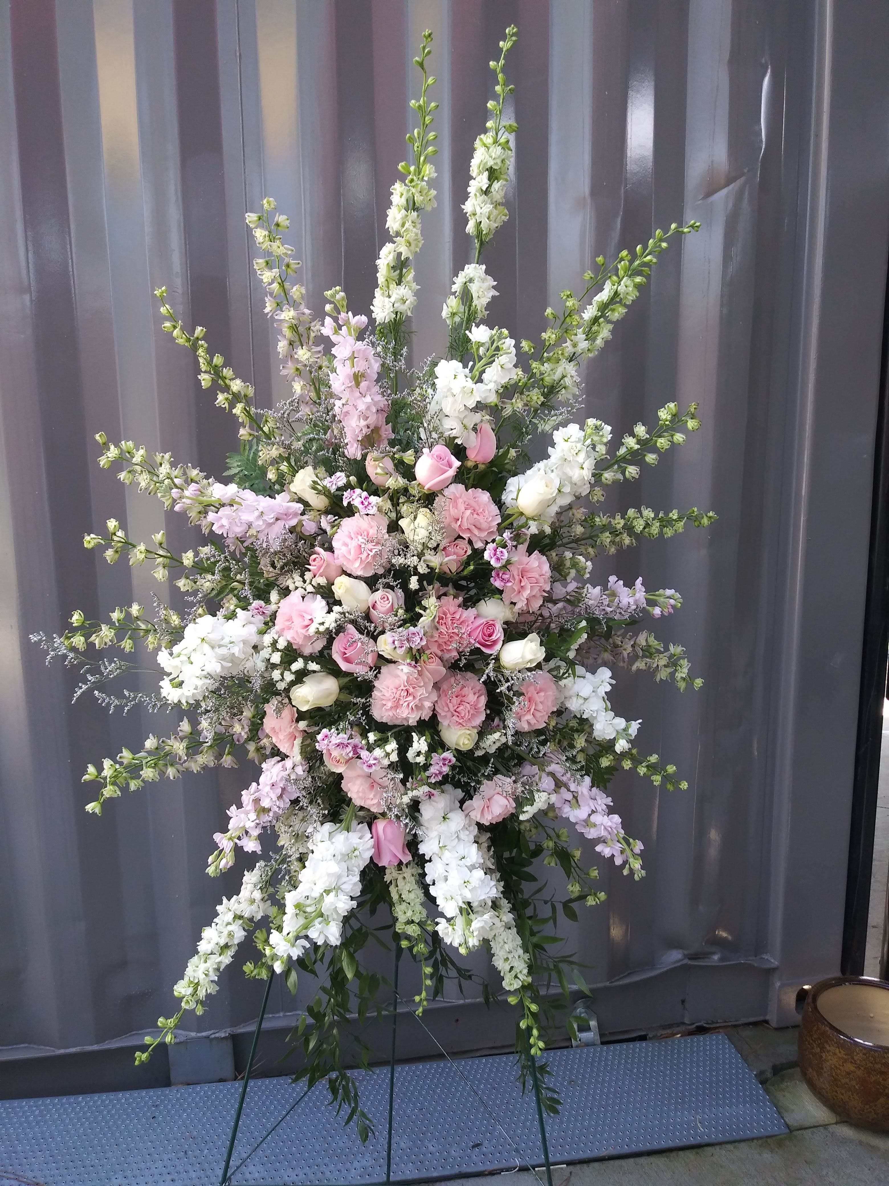 Queen's Tribute Standing Spray Queen's Tribute Standing Spray - A captivating floral arrangement of soft pink roses and carnations, larkspur, cream roses, white stock, white delphinium, soft lavender stock, Italian Ruscus, caspia, and assorted greenery.