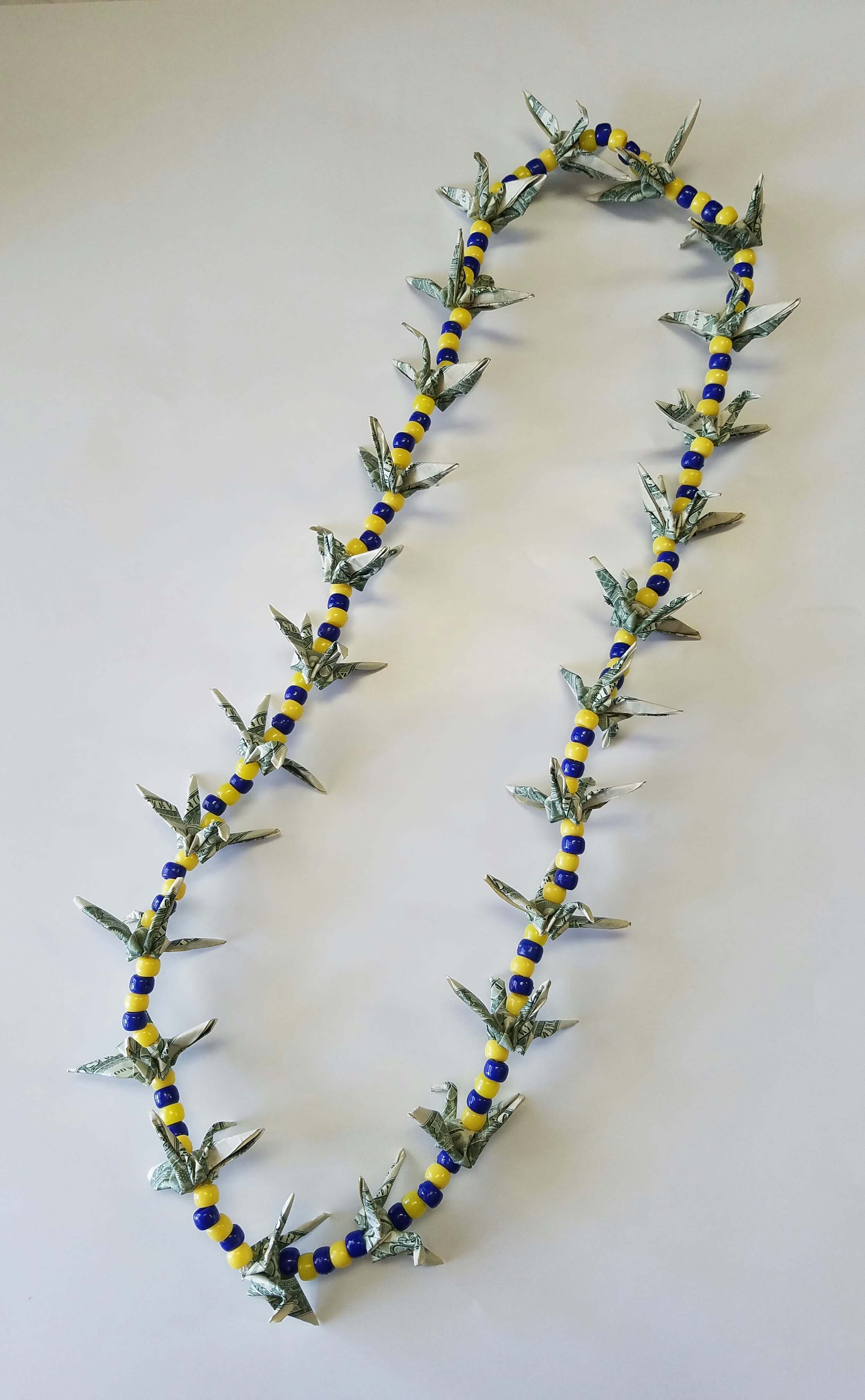 Crane money lei ( blue and gold ) Crane money lei ( blue and gold ) - 25 - $1.00 bills folded into a shape of a crane. This lei can used for graduation, birthday,or wedding as a gift.Crane are said to bring long term happiness. These Cranes can be unfold in the center and the money still be used. NO RETURN OR REFUND. ALL SALES ARE FINAL