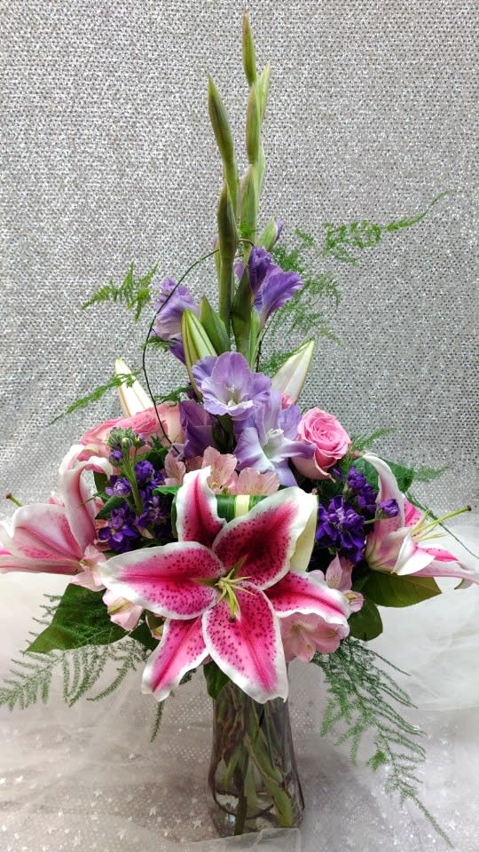 Striking Beauty - This lovely lavender and pink arrangement is beautifully designed in a vase. Contains stargazer lilies, purple gladiolus, pink roses, purple stock, and various filler greens.  Dimension: 30&quot;x17&quot;