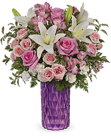 Teleflora's Rose Glam Bouquet - Bursting with perfect pink roses and snow white lilies, this sparkling cut glass vase in the most glamorous shade of amethyst is a Mother's Day gem. This bouquet features pink roses, pink spray roses, white asiatic lilies, miniature white carnations, pink alstroemeria, pitta negra and leatherleaf fern. Delivered in Teleflora's Amazing Amethyst vase. Orientation: All-Around